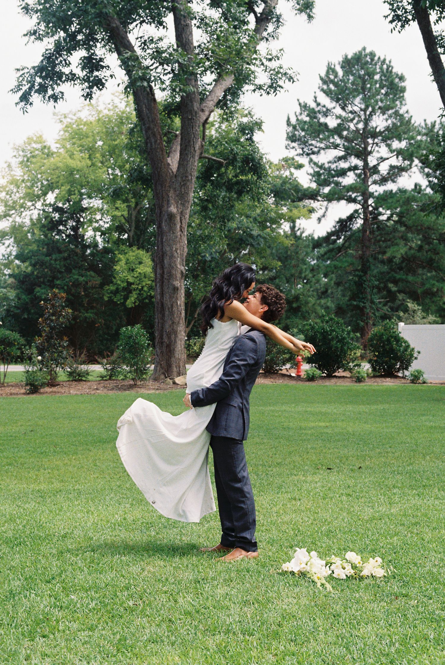Wedding couple performs romantic dip poses in sequence on green lawn with white floral bouquet.