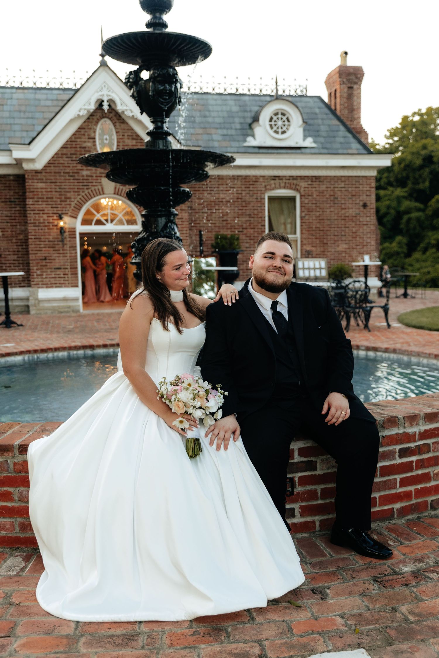 Newlyweds share playful moments on brick steps near a historic building.