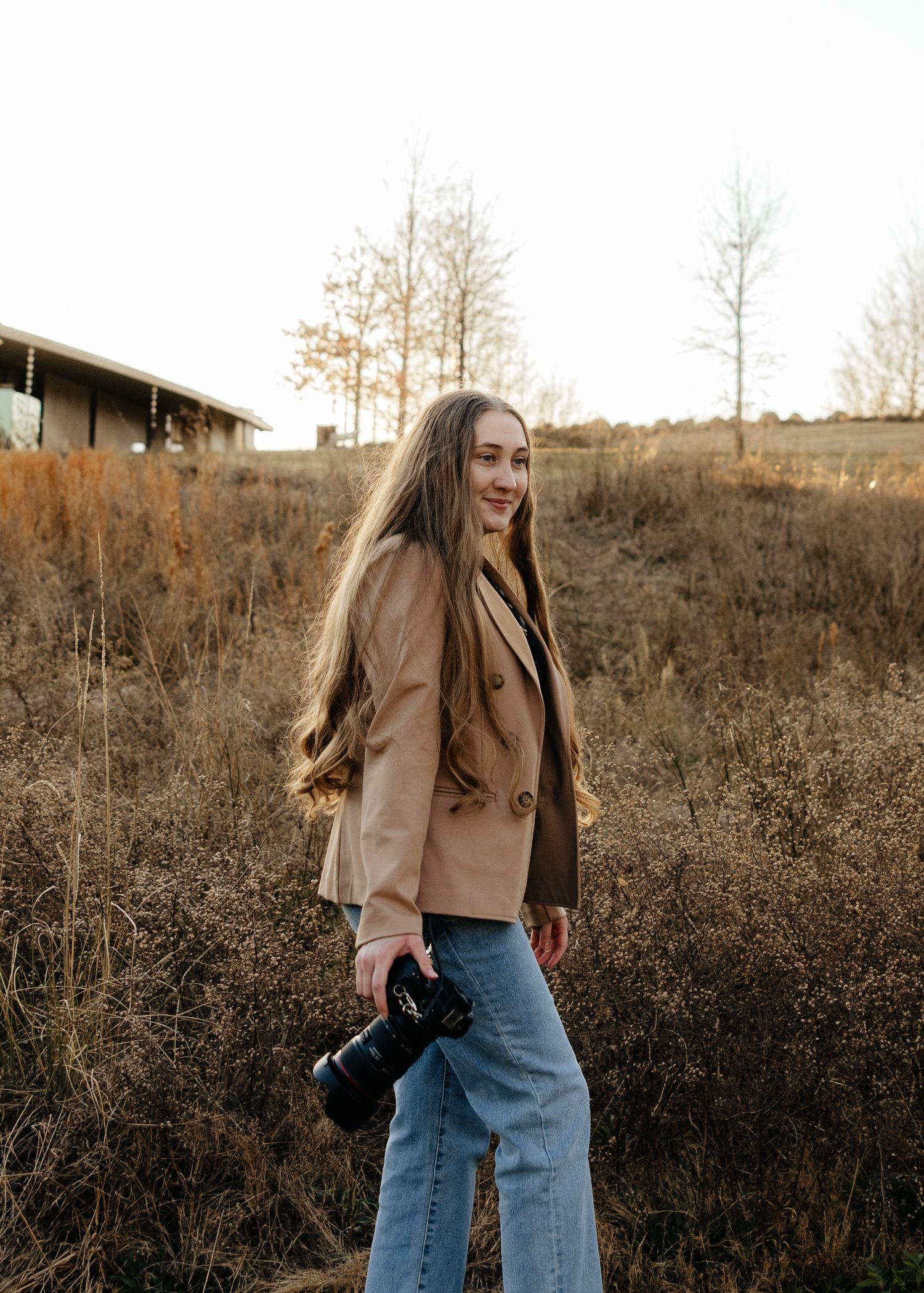 Portrait photography of a photographer in a grass field setting during golden hour.