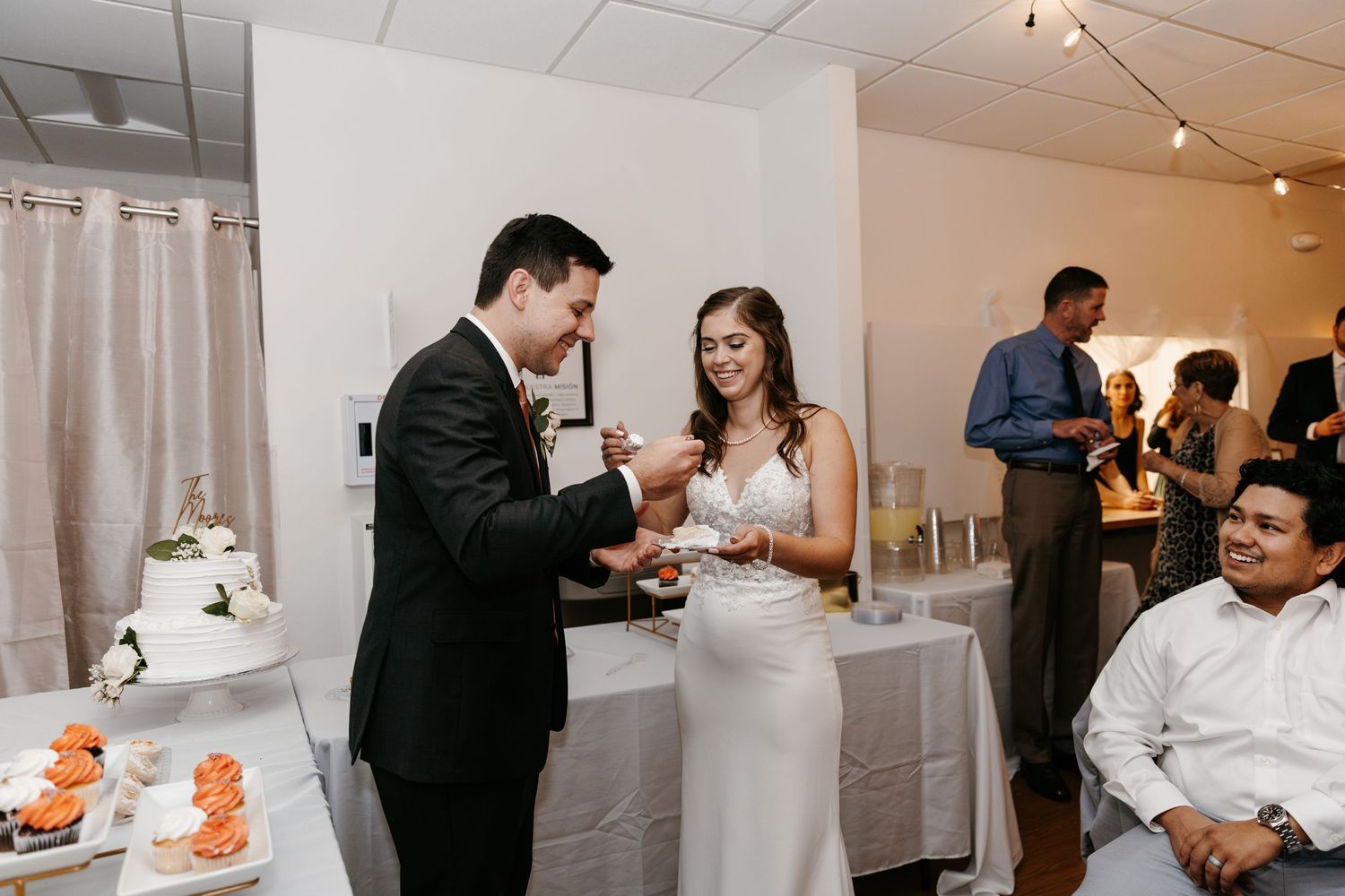 Newlyweds share a sweet moment while cutting their wedding cake at an indoor reception.