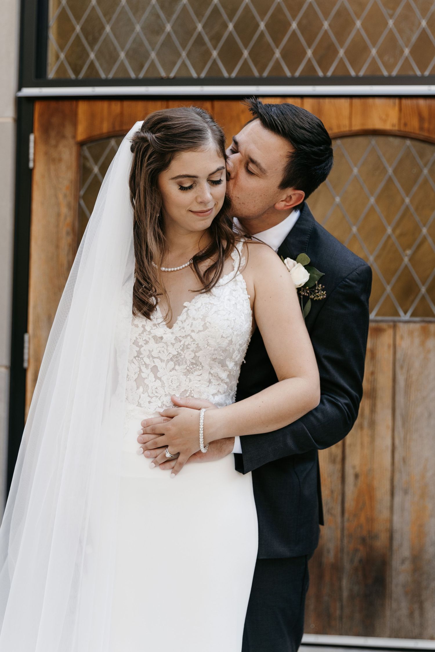 Intimate wedding photos showing tender moments between newlyweds against a wooden door backdrop.
