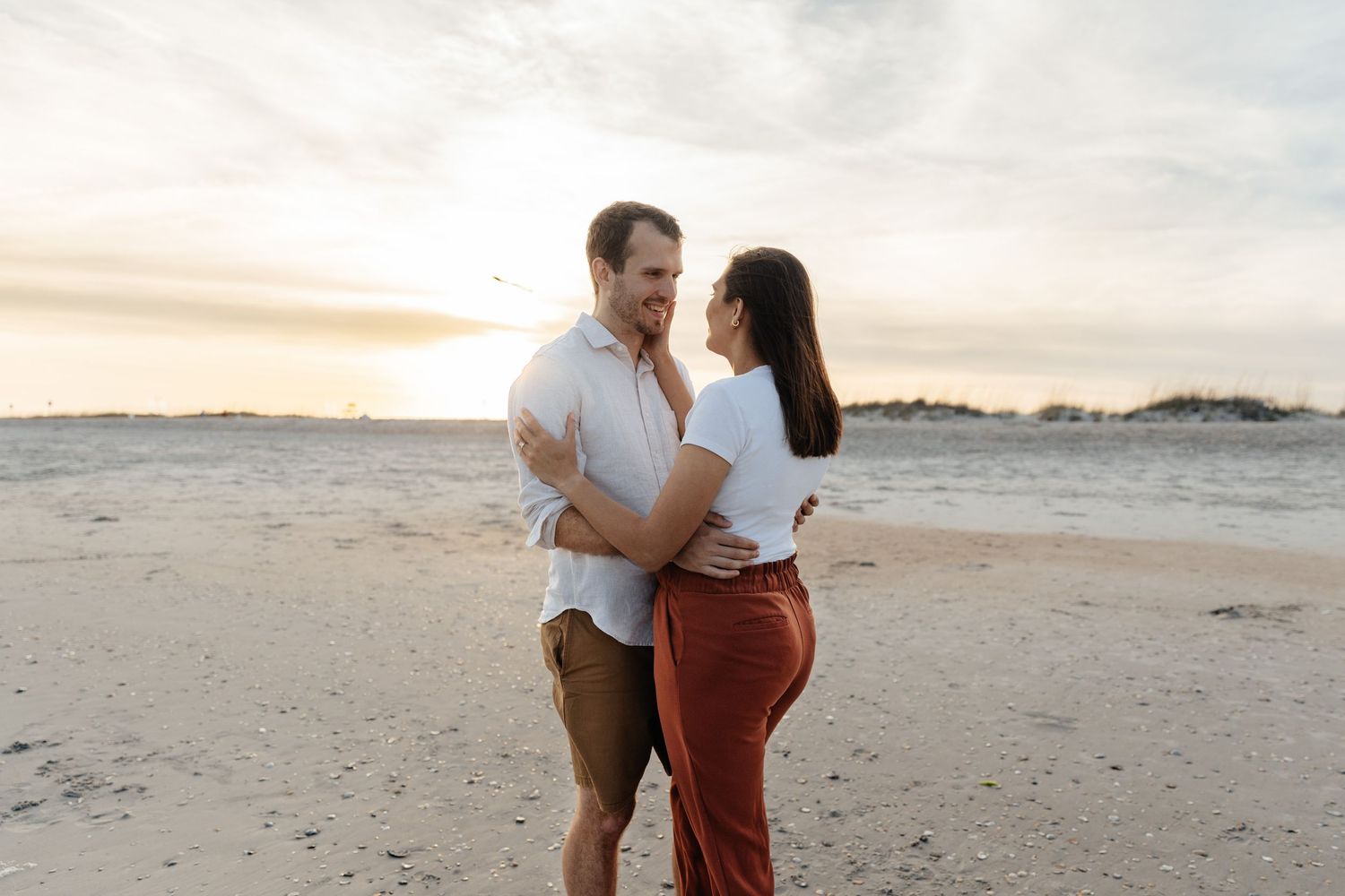 Romantic couple photoshoot on a sandy beach during sunset.