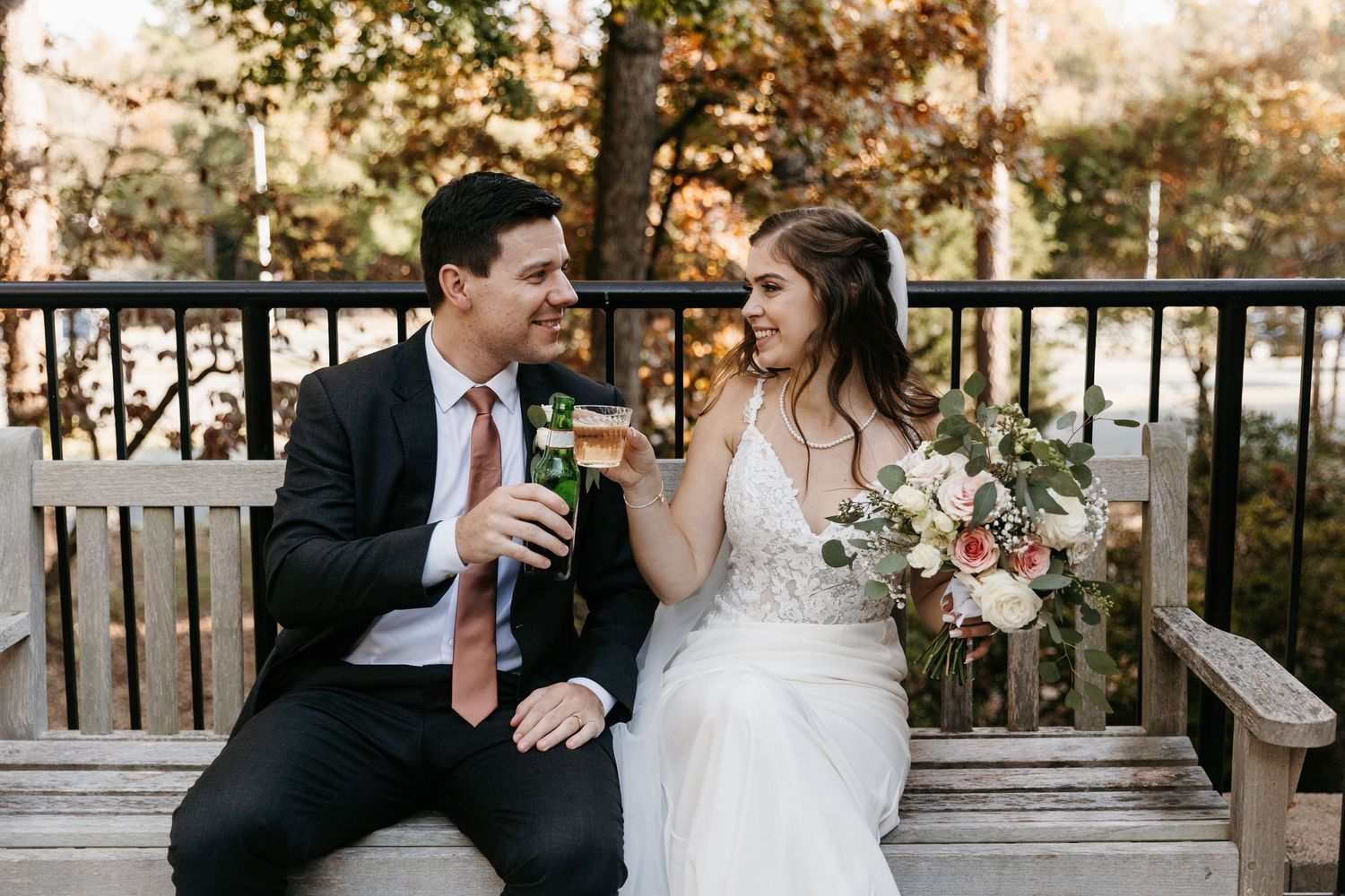 Autumn wedding portraits on a wooden deck with golden foliage in the background.
