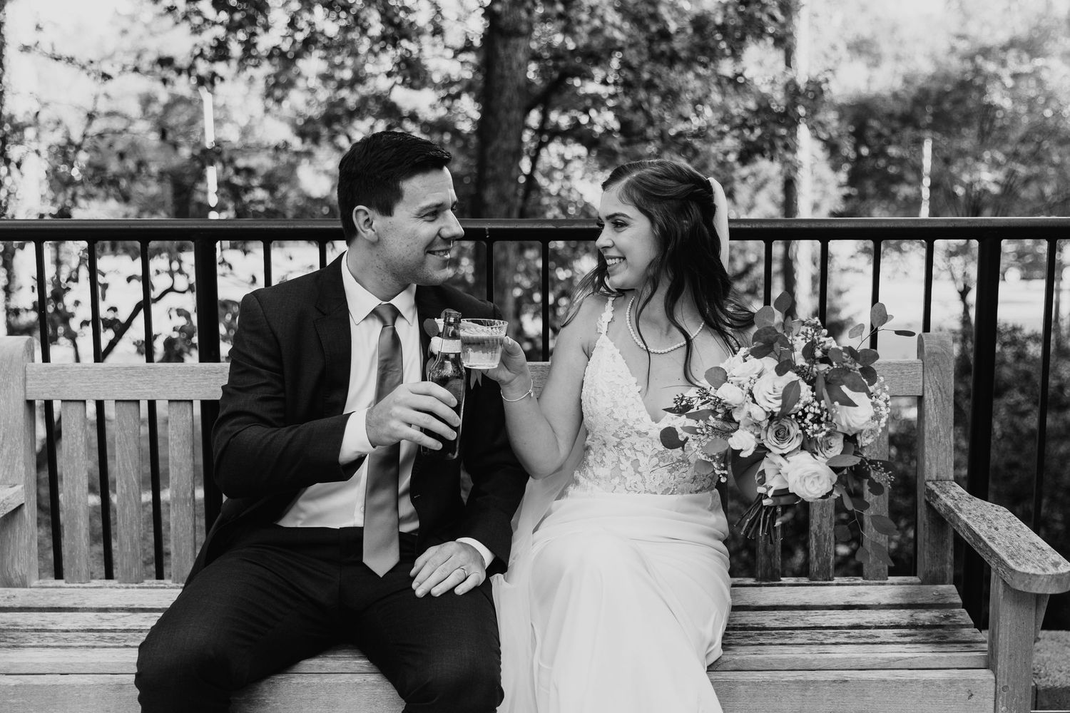A romantic wedding couple shares intimate moments on a wooden bench during golden hour.