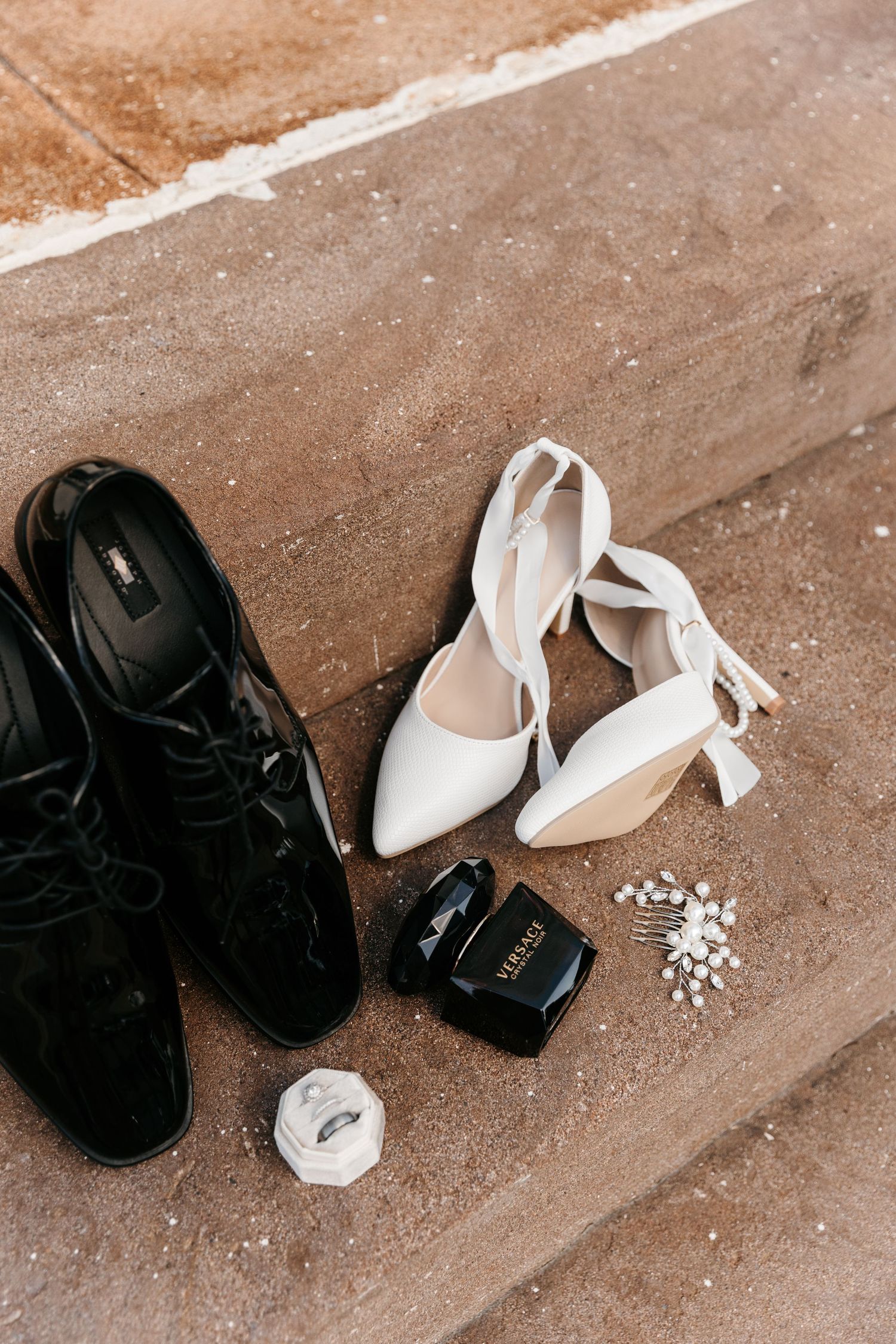 Wedding shoes and accessories scattered on brick stairs.
