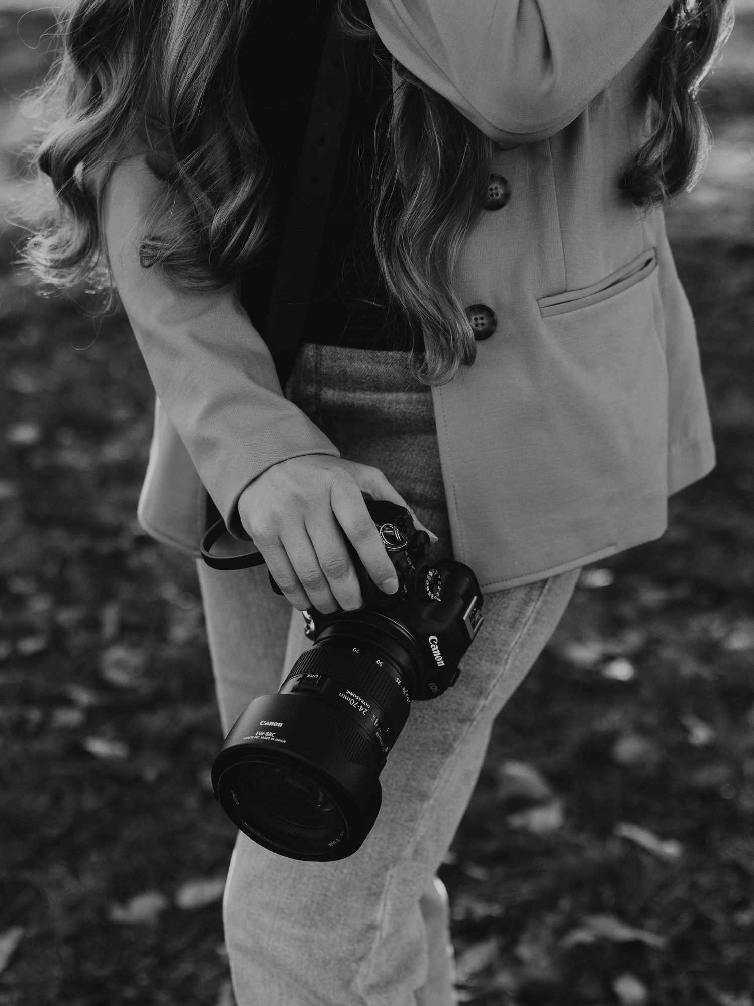 Close-up shot of hands holding a professional camera in black and white.