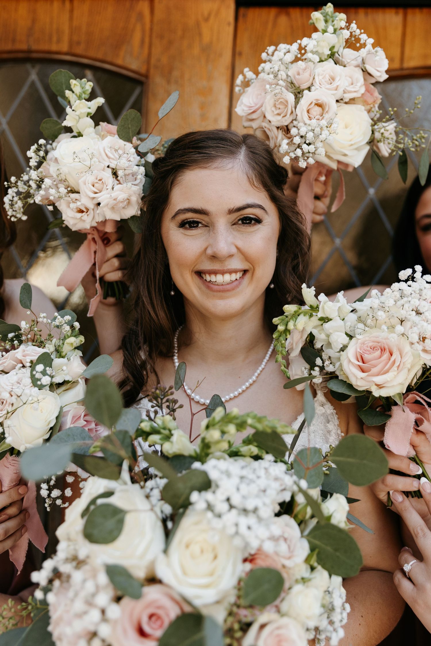 Bride surrounded by elegant bridal bouquet features blush roses, white flowers, and eucalyptus greenery.