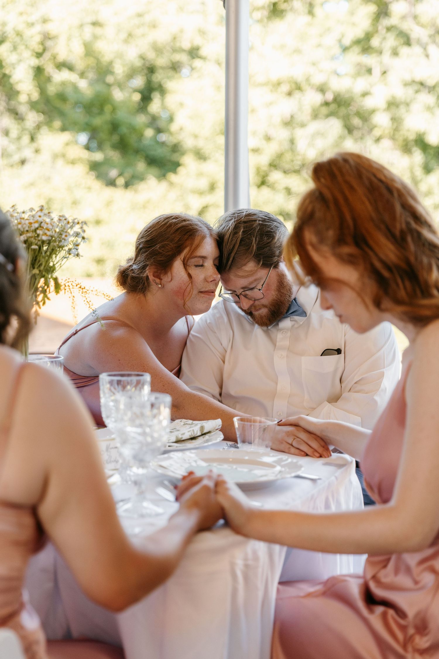 Wedding guests share a moment of pray during an outdoor reception dinner.