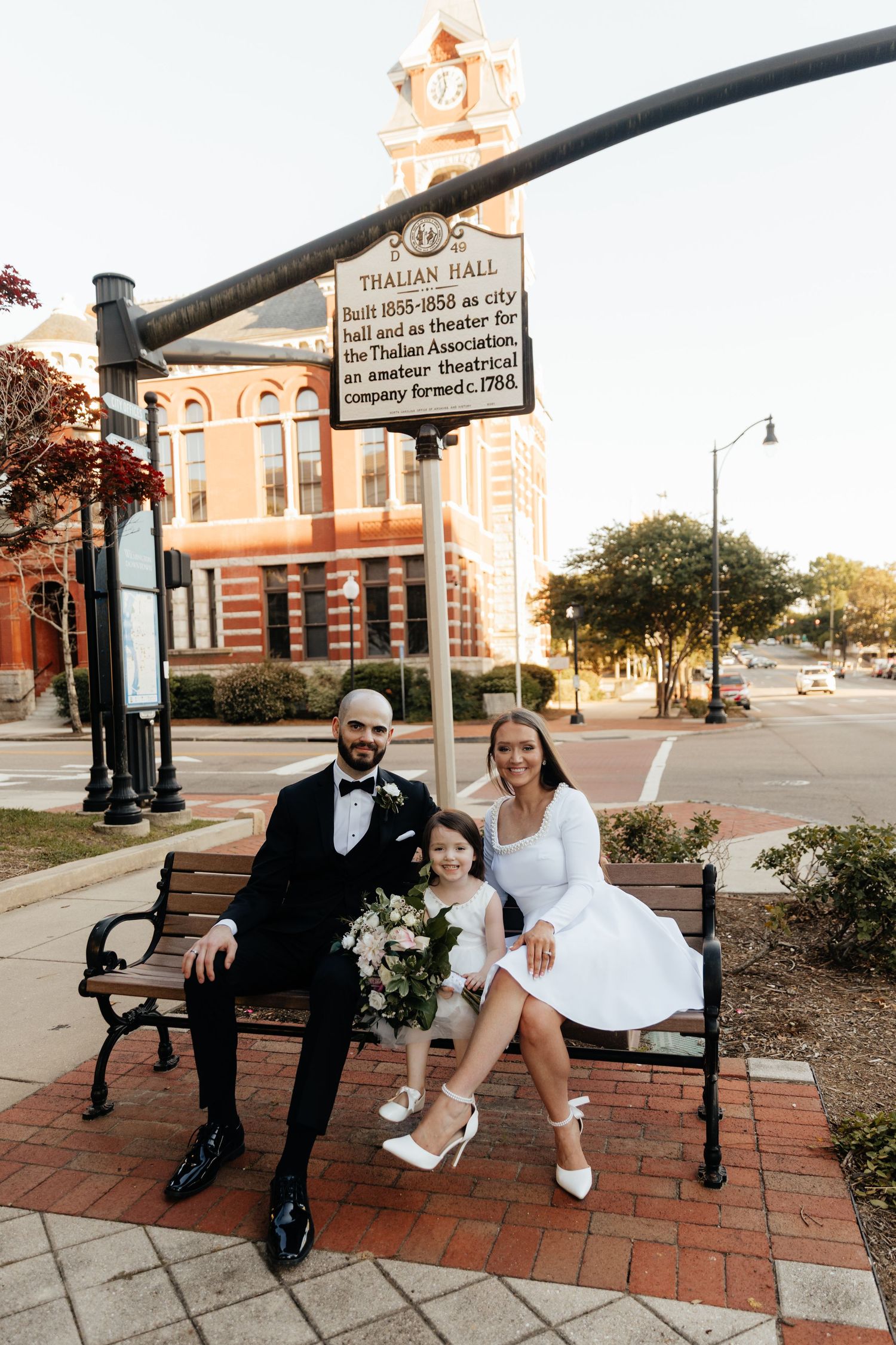 Couple shares intimate moments on a brick patio with decorative bench and historic building backdrop.