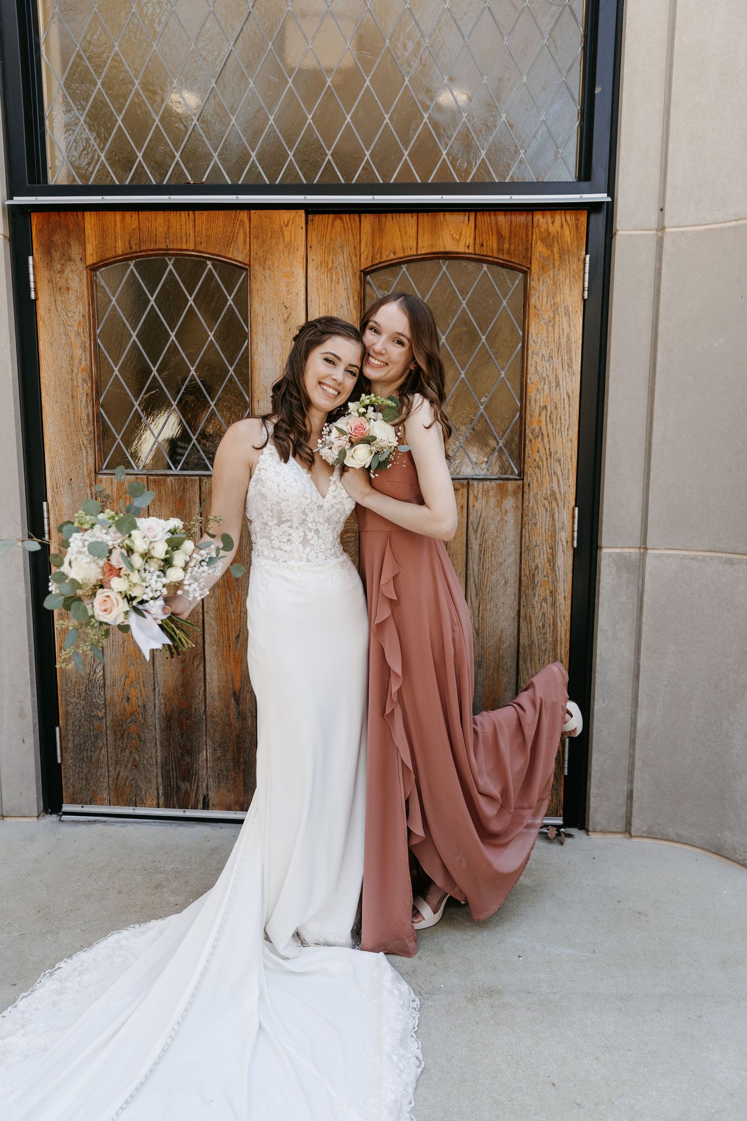 Candid moments captured between bride in lace gown and bridesmaids in dusty rose dresses.