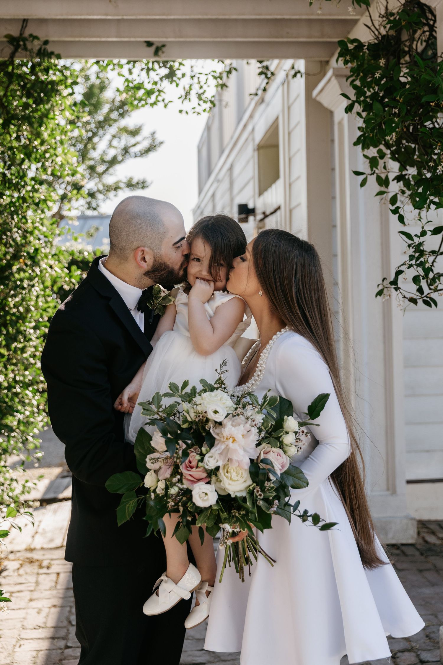 A tender family moment captured outside with a beautiful floral bouquet and white dress details.