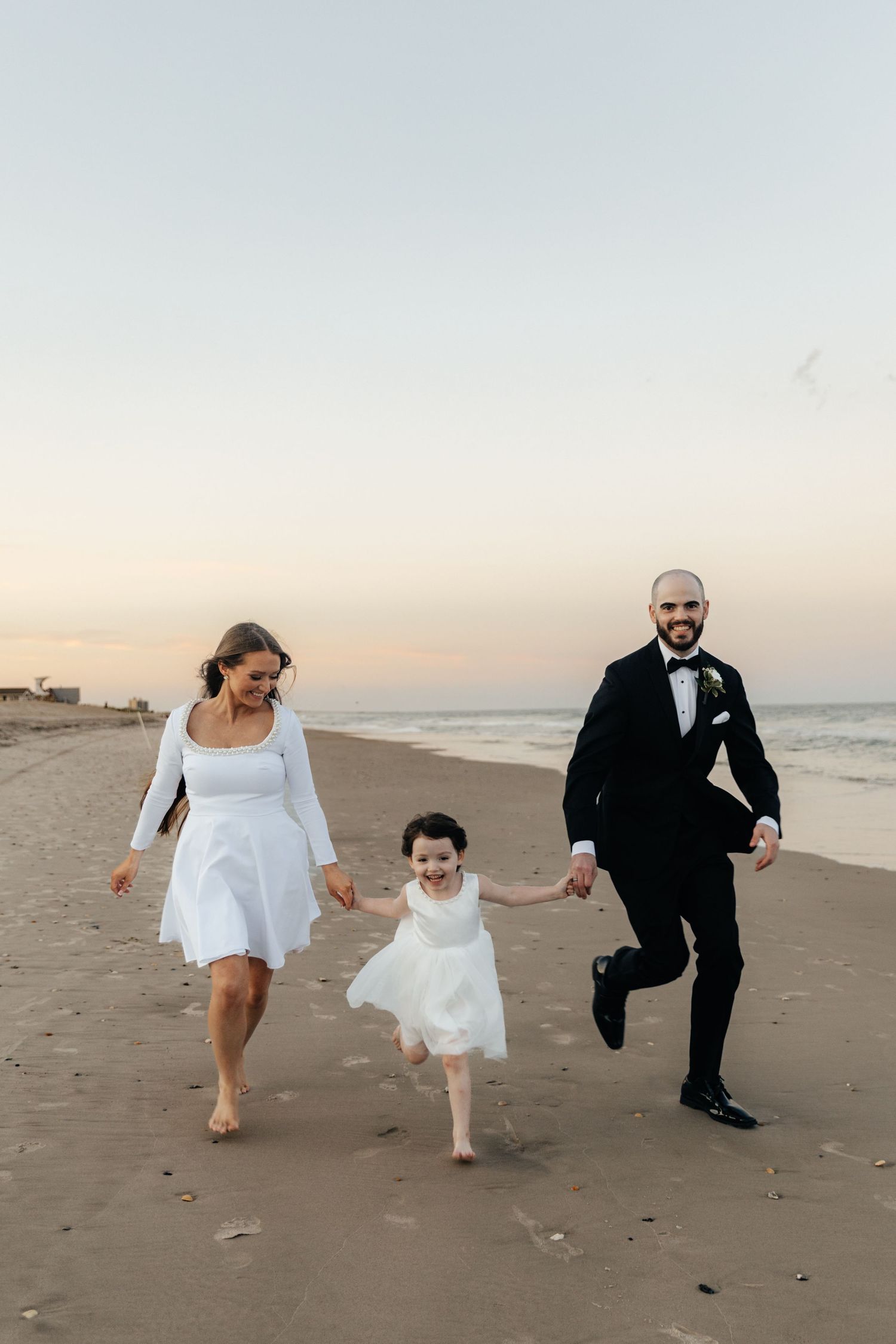 A joyful family running together on the beach during sunset.