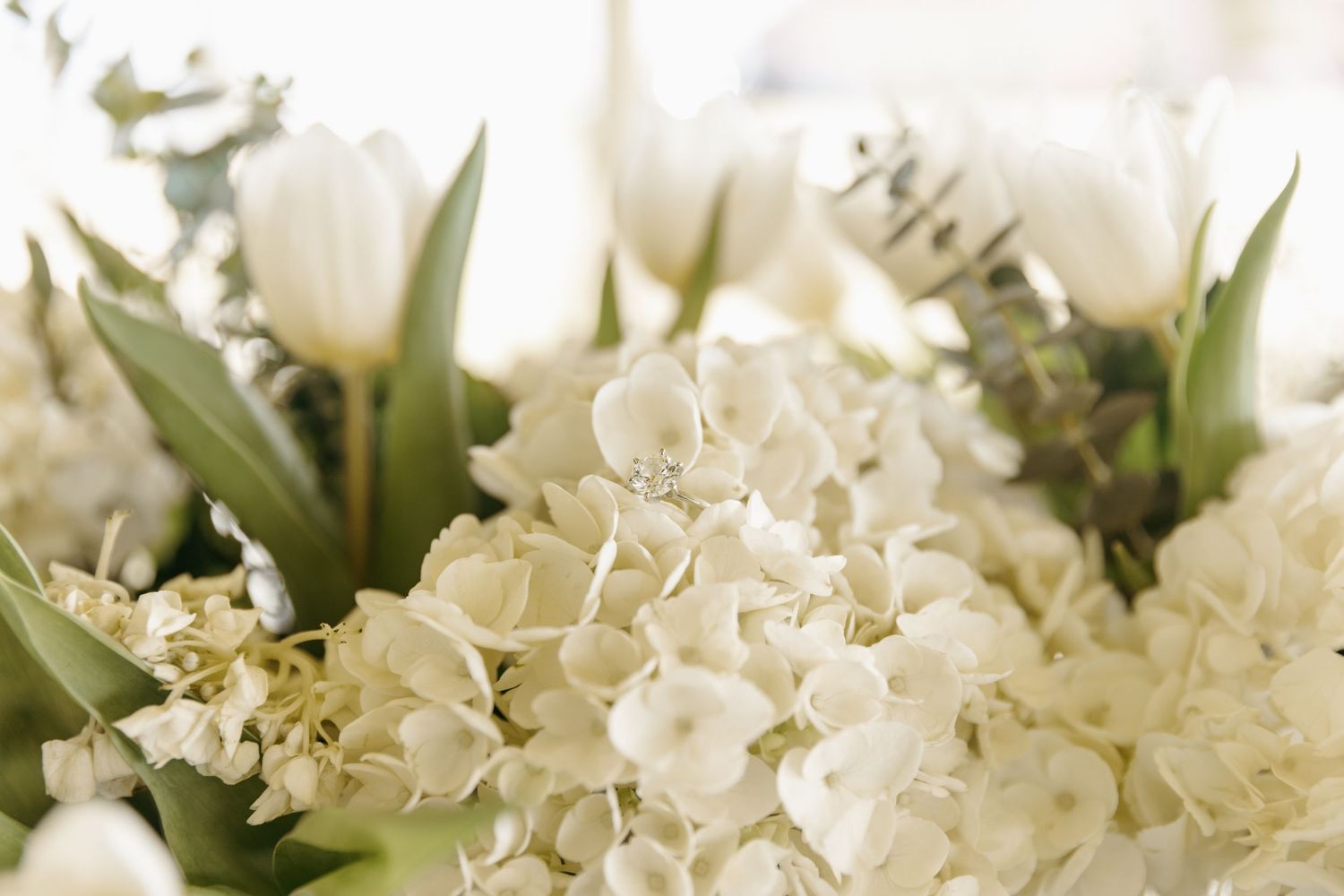 Elegant ring detail shot within a white hydrangea and greenery floral arrangement.