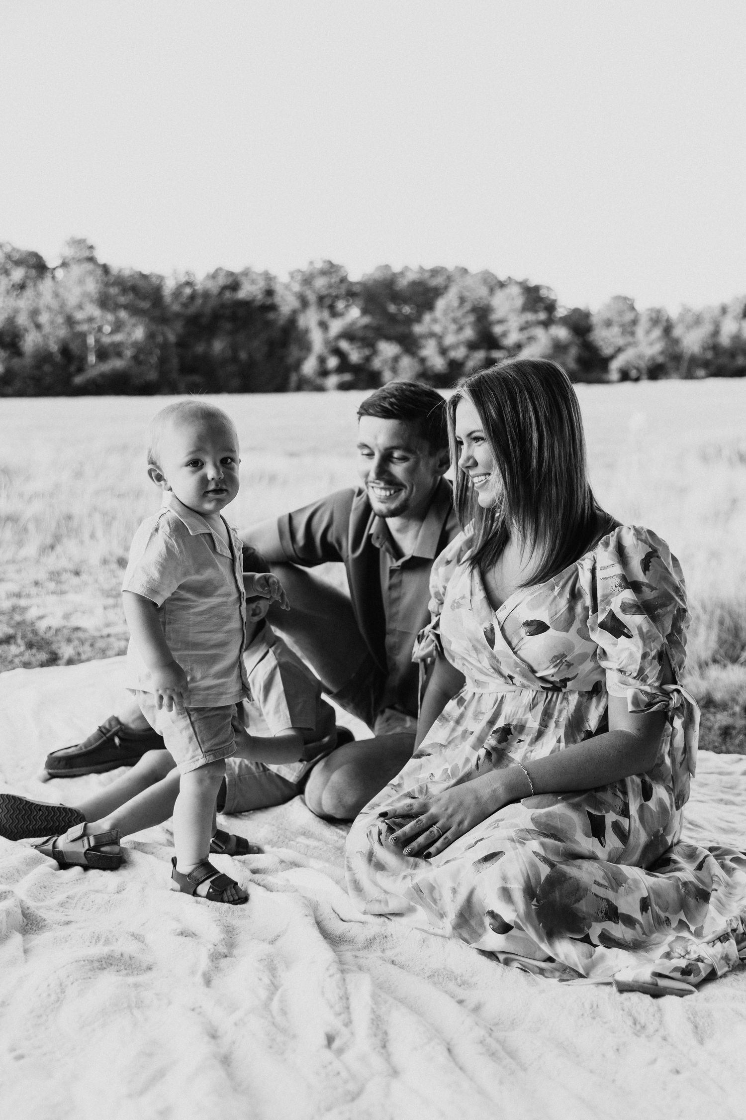 Family enjoying a relaxed picnic together on a blanket in a sunny field.