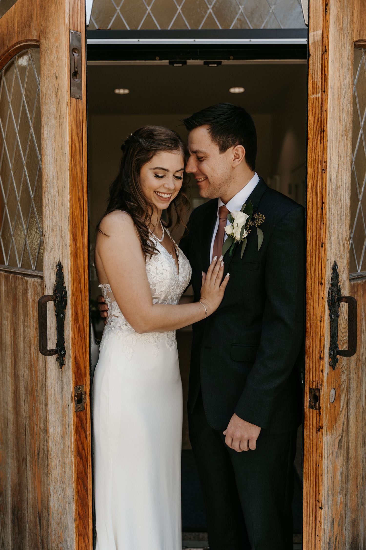 Candid wedding moments captured in front of a rustic wooden doorway.