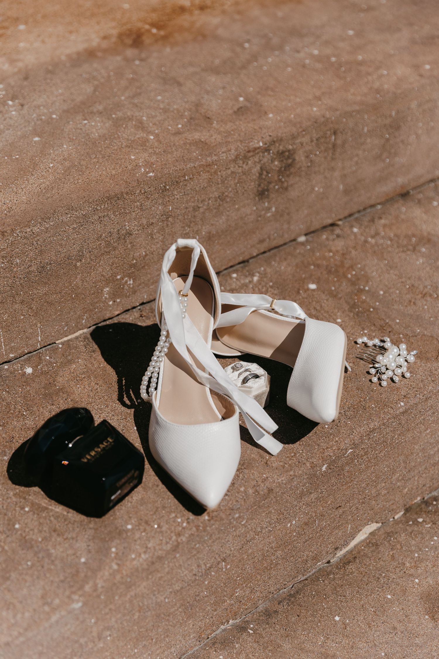 Wedding shoes and accessories arranged artistically on brick stairs.