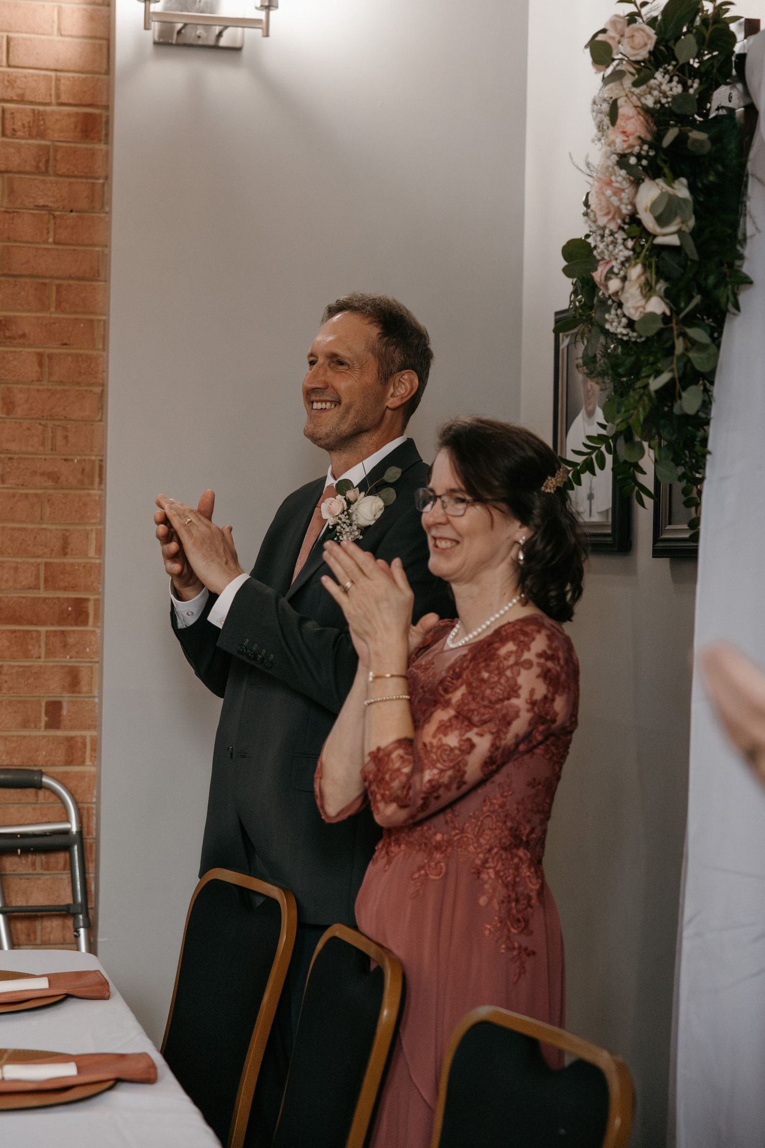 Wedding guests react emotionally during reception speeches in an elegant brick-walled venue.