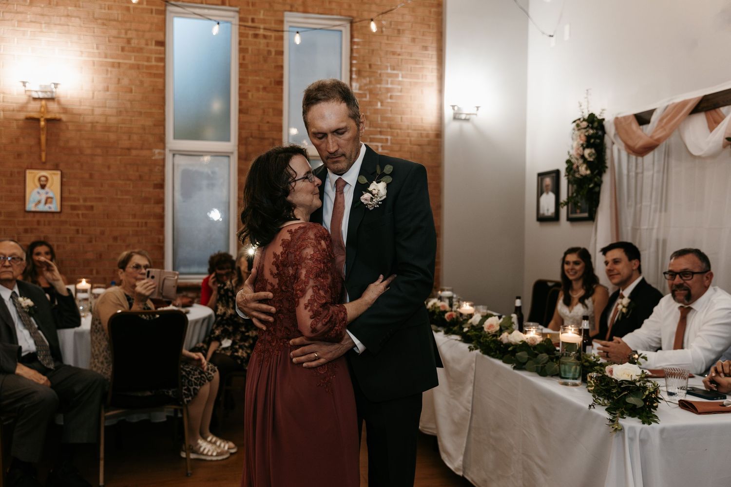 Wedding reception in a charming brick venue with guests mingling at decorated tables.