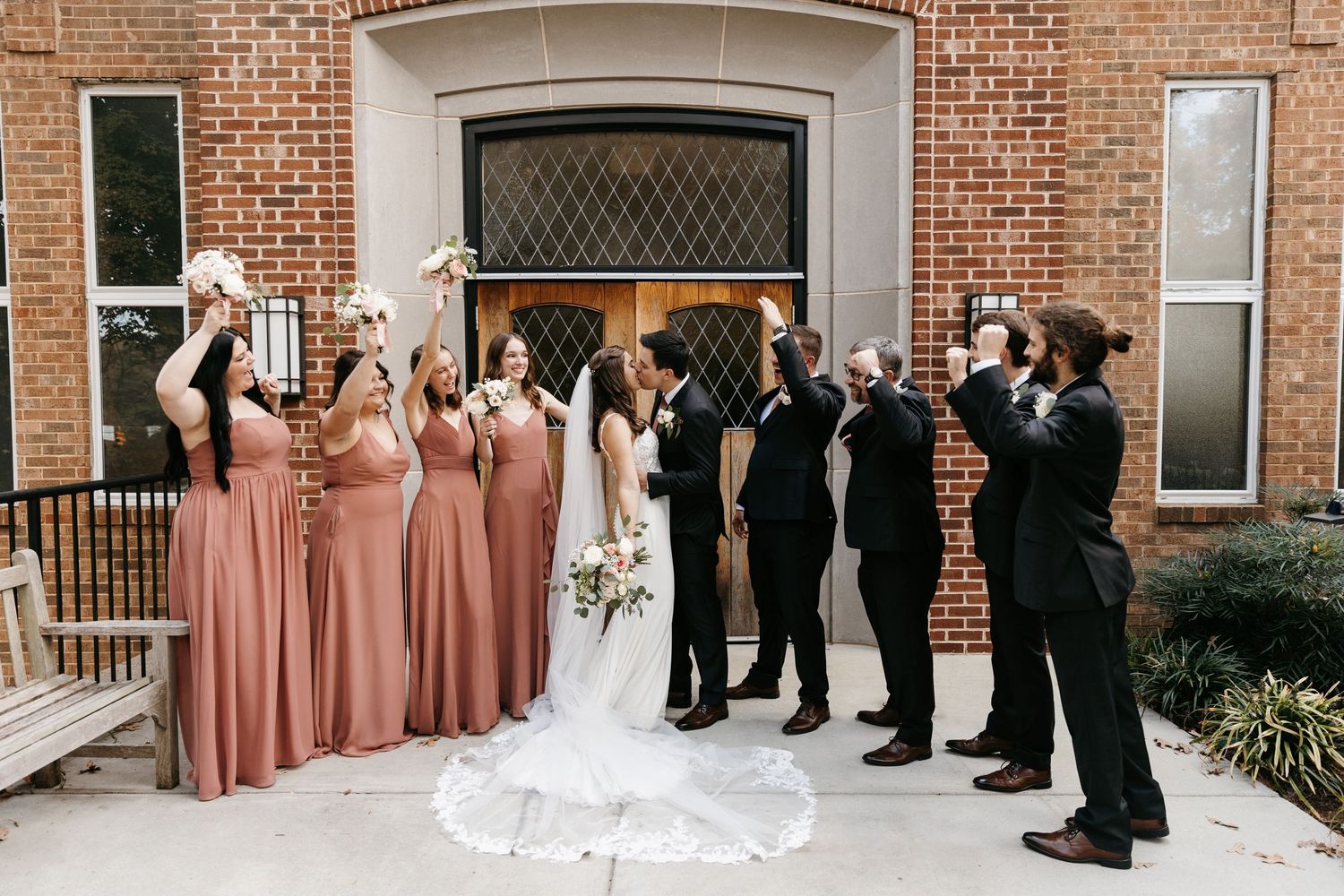 Full wedding party photo session outside brick church with formal and candid moments.
