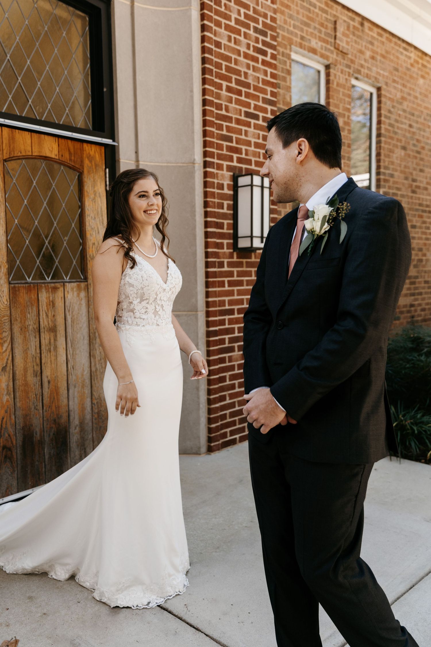 Candid wedding moments captured outside brick church with wooden doors.