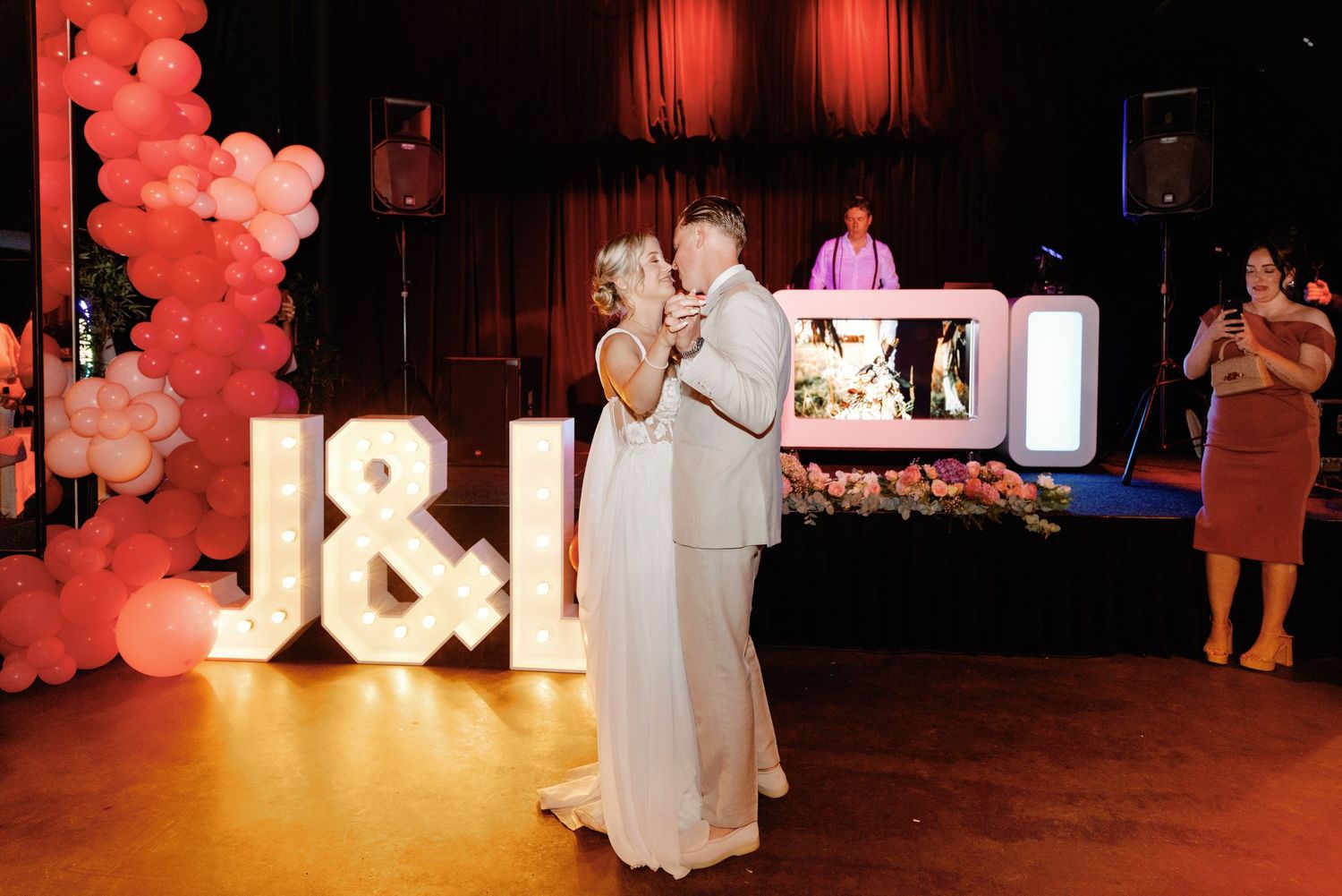 Illuminated letters and red balloon decorations create a romantic ambiance at an indoor event venue.