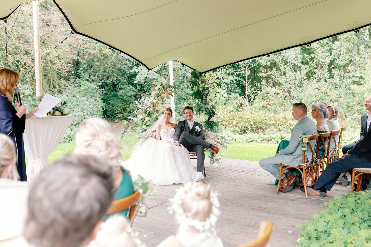 People gather under a covered outdoor area for a social event on a sunny day.