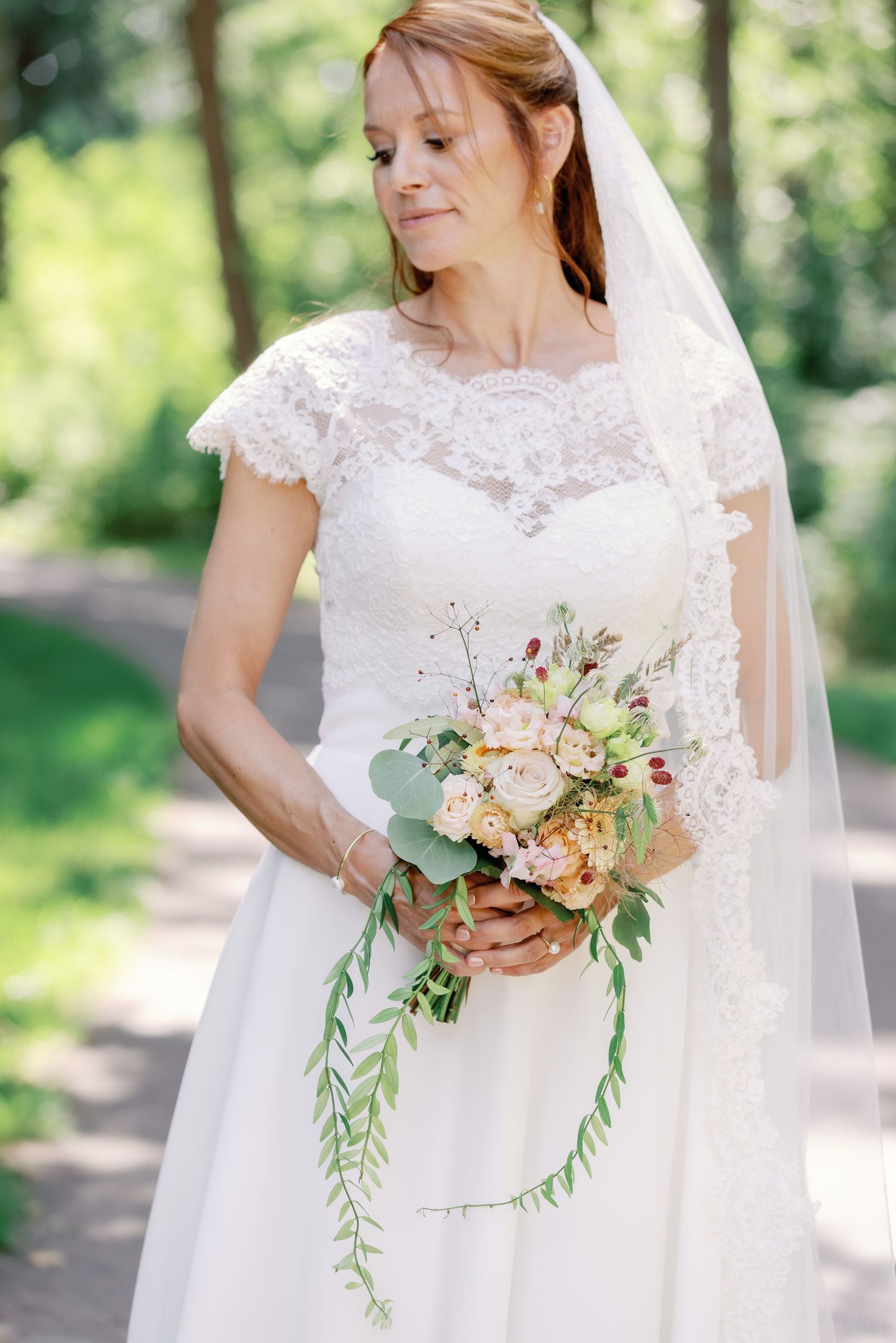 A bridal portrait series showing a white lace wedding dress and delicate peach and eucalyptus bouquet in natural light.