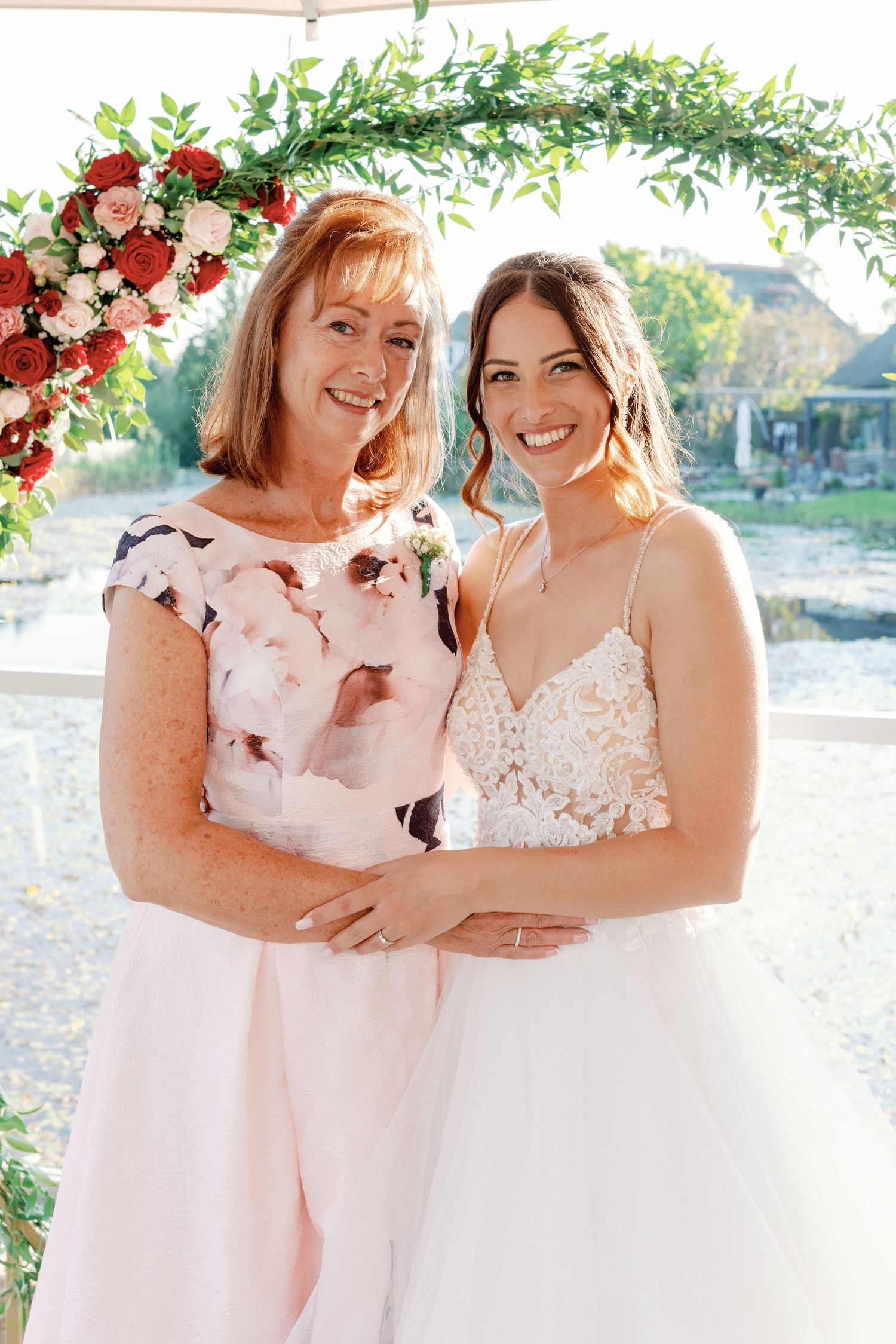 Wedding party members in pink and white dresses share joyful moment outdoors.