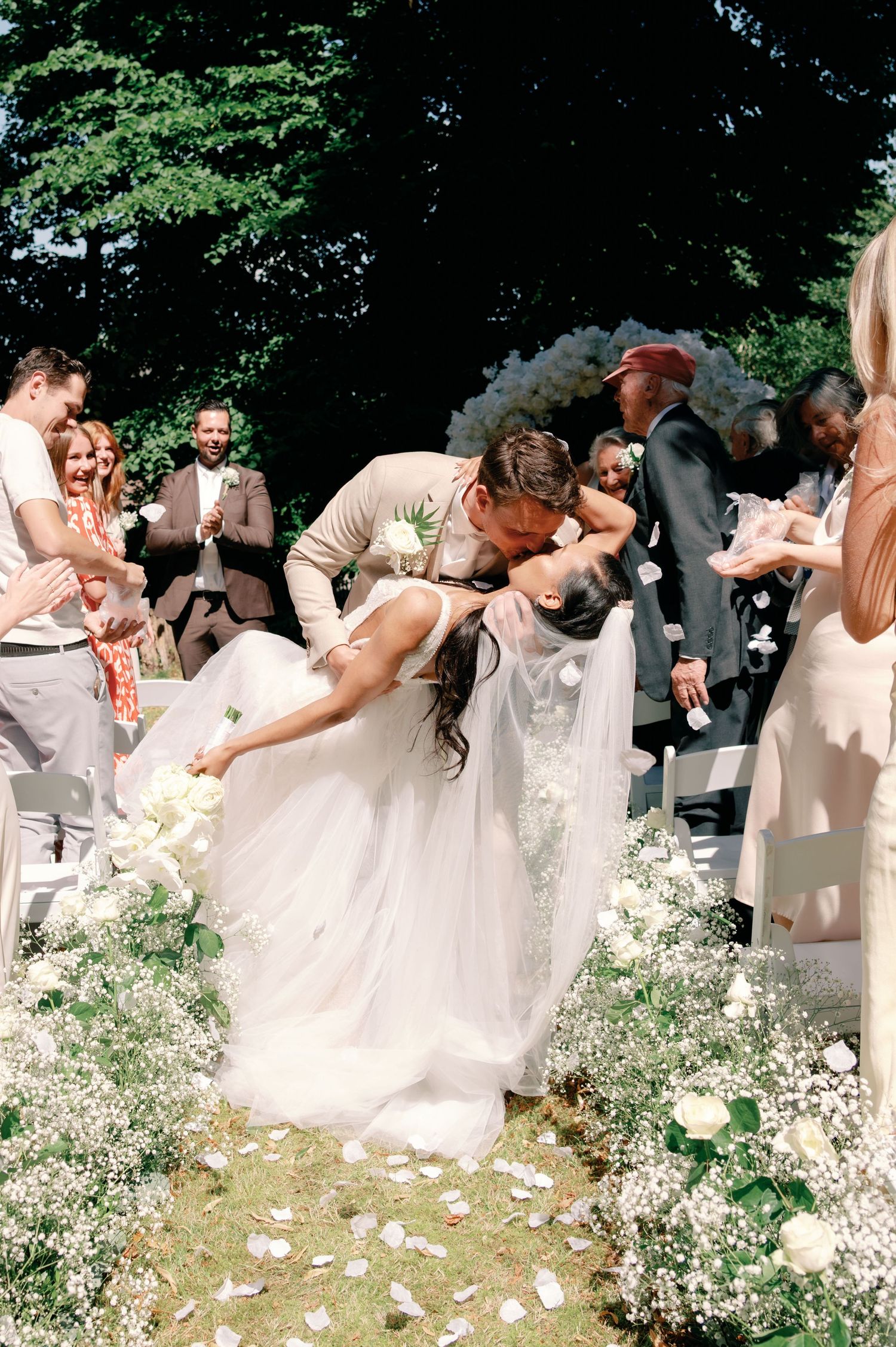 Wedding party poses outdoors with white baby's breath flowers and light colored dresses in a garden setting.