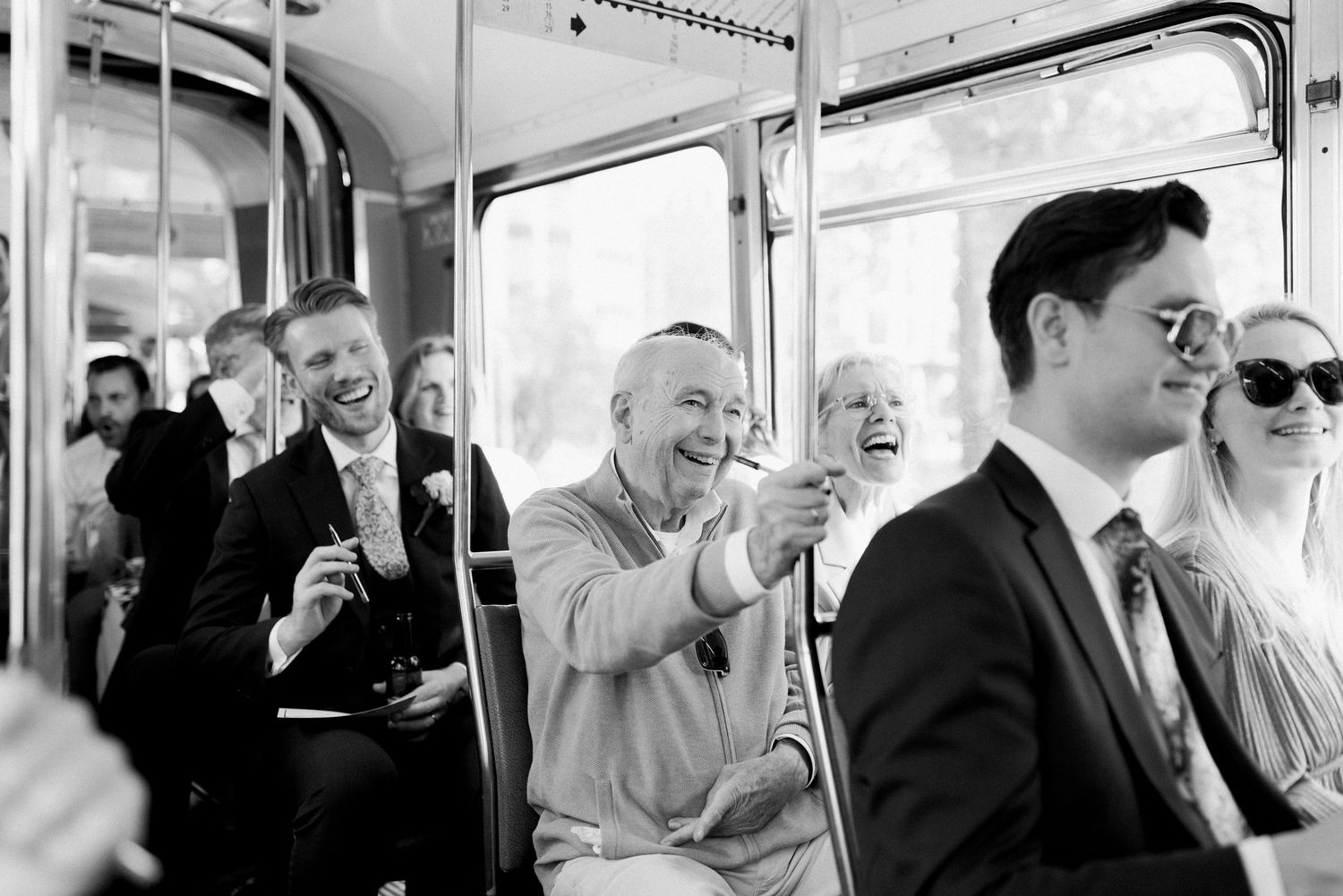 Candid black and white photos show groups of commuters smiling and laughing together on public transportation.