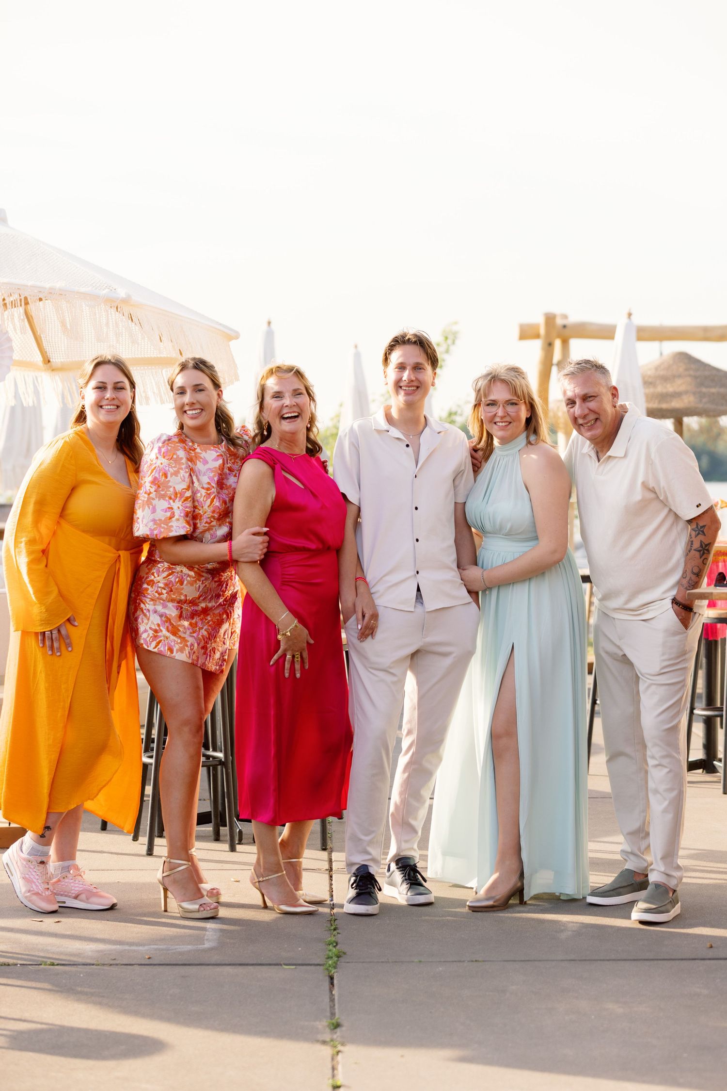 Wedding party in colorful summer attire posing together at sunset.