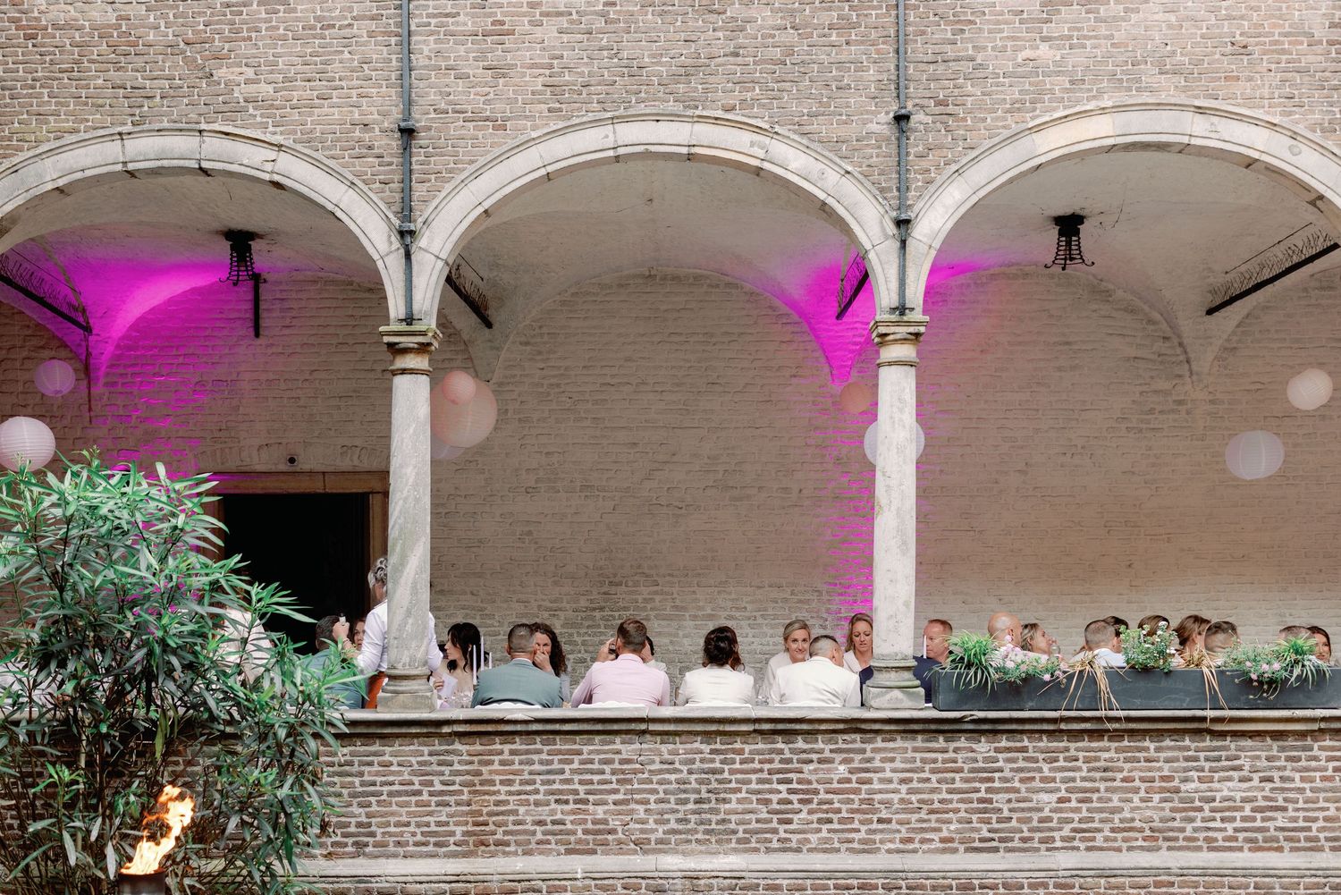 A panoramic view of an elegant arched colonnade with pink lighting illuminating the architectural details.