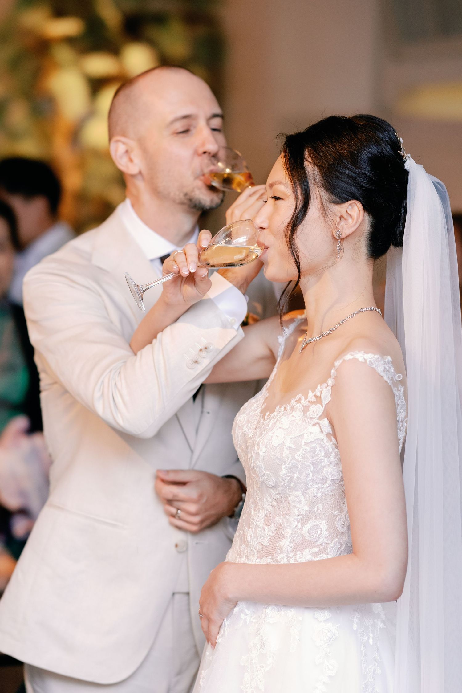 A wedding couple shares a playful moment while feeding each other cake during their reception celebration.
