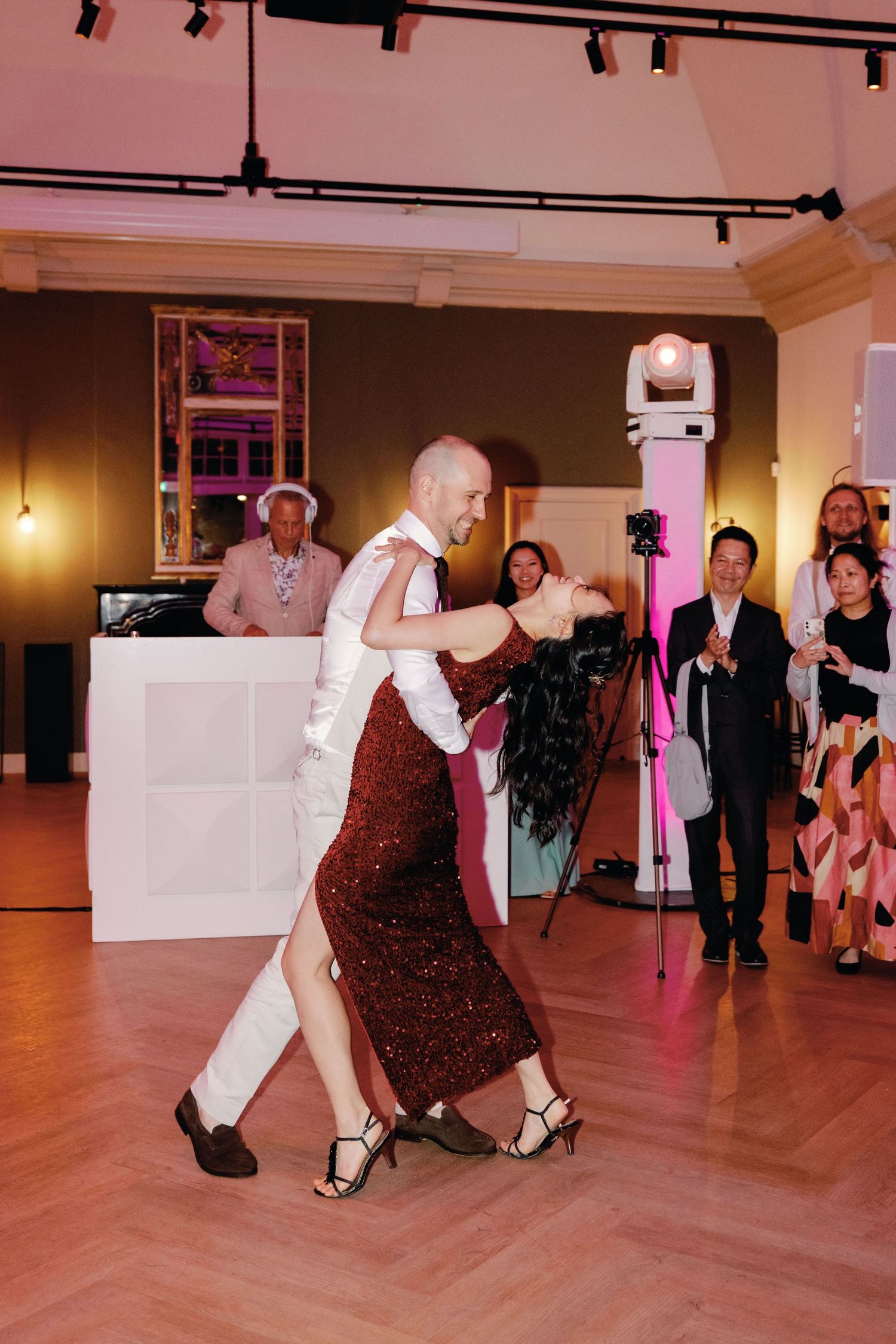 Dancers perform a sequence of dips and spins on a wooden dance floor during a social dance event.