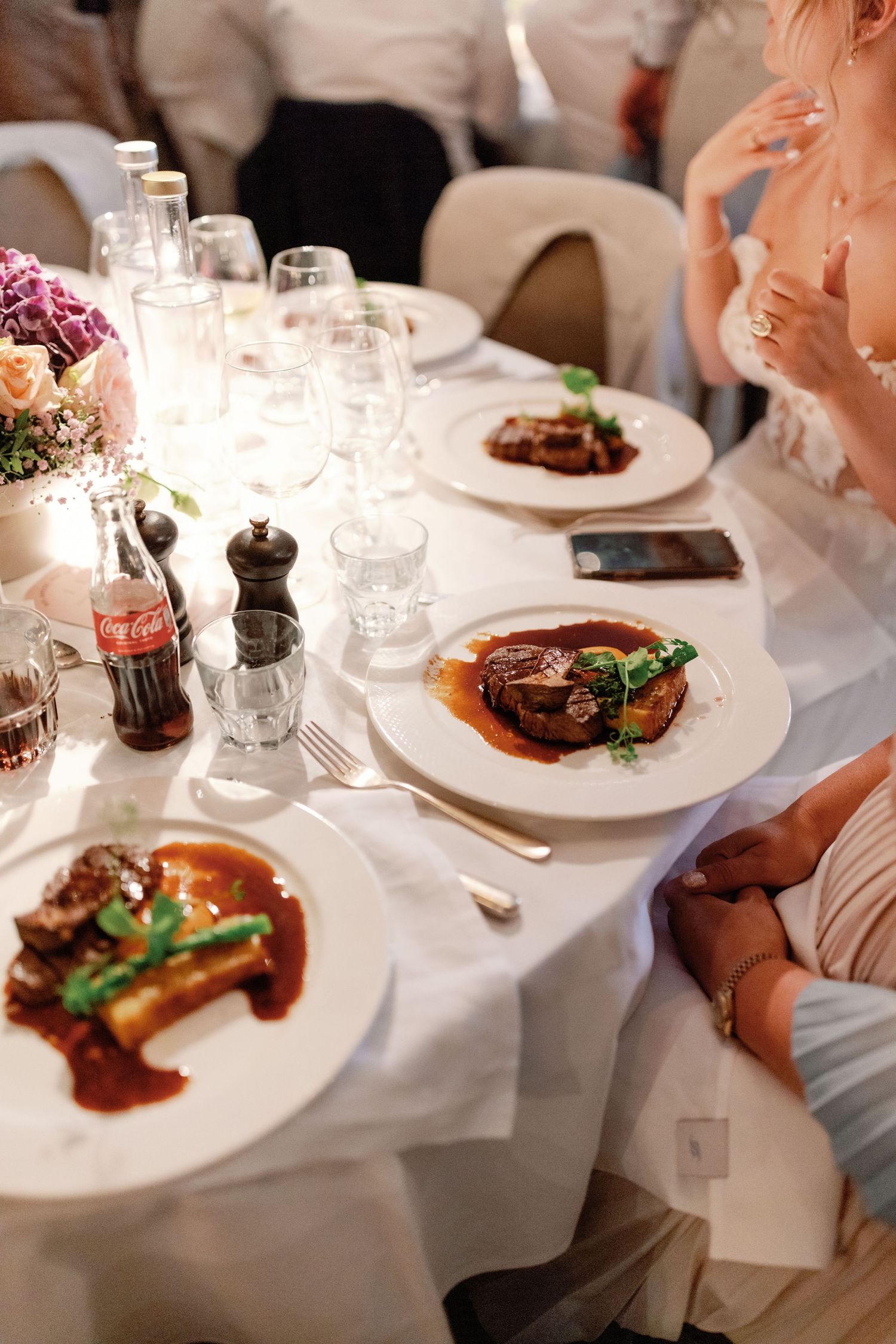 Elegant dinner service at upscale restaurant with white tablecloths and plated entrees served with red wine sauce.