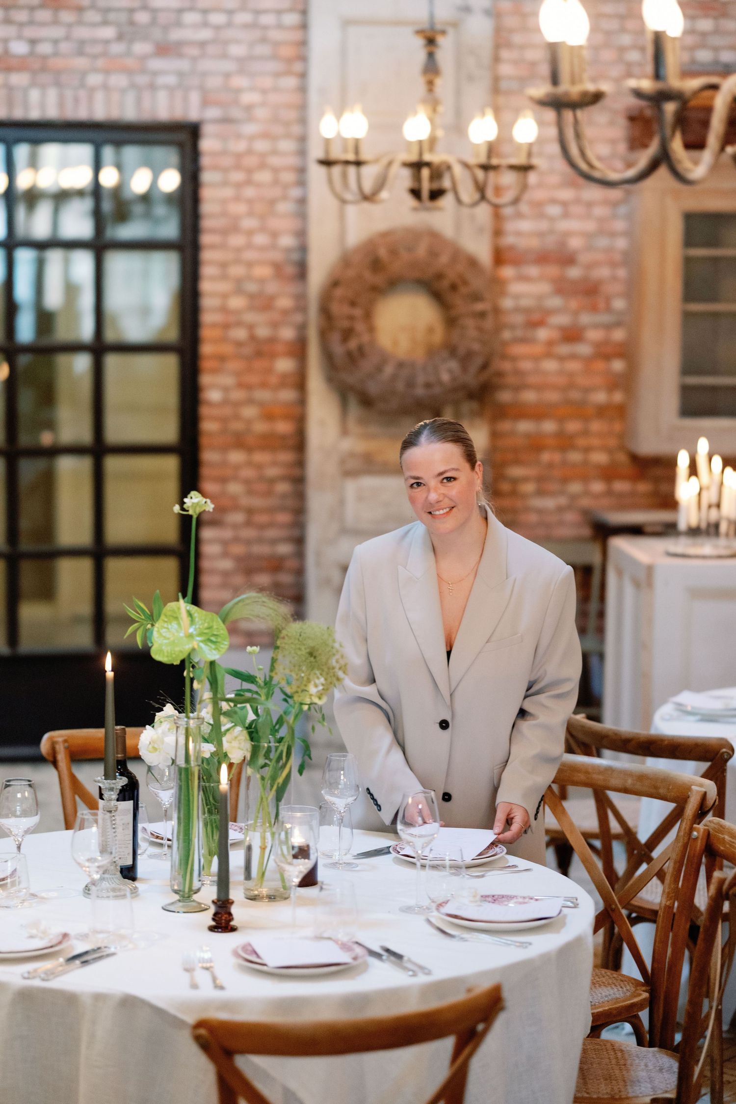Elegant table settings with white linens and floral centerpieces in a rustic brick-walled restaurant dining room.