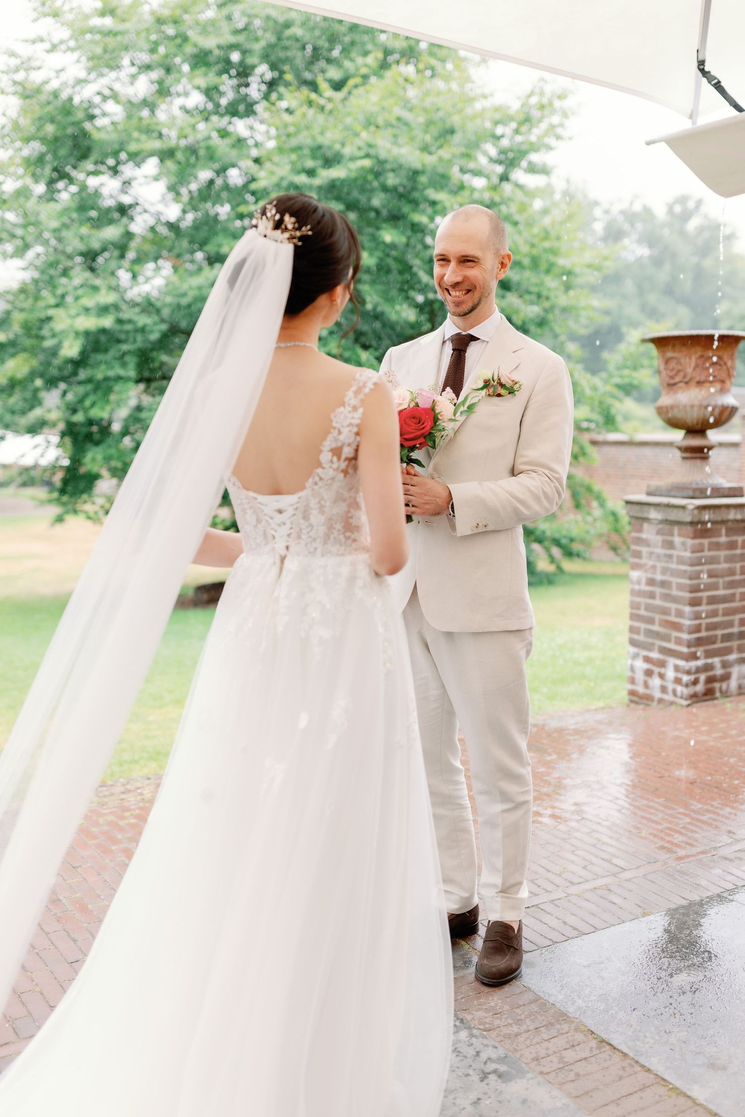 Romantic first look sequence between newlyweds on an outdoor brick terrace surrounded by greenery.