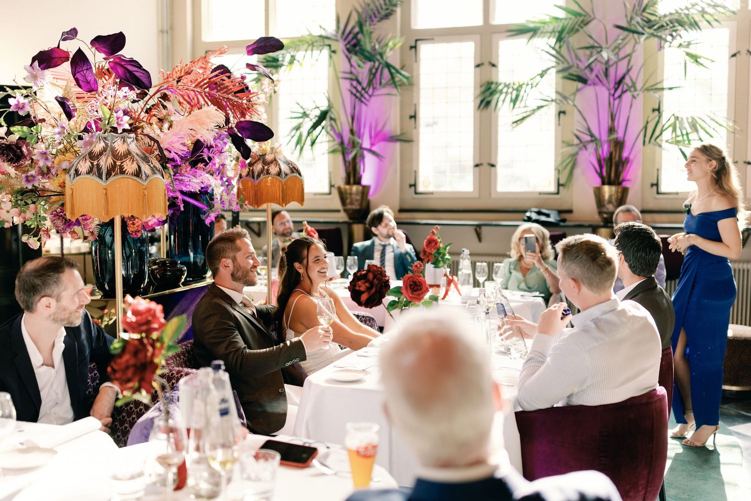 Wedding reception table settings with vibrant pink and purple floral centerpieces.