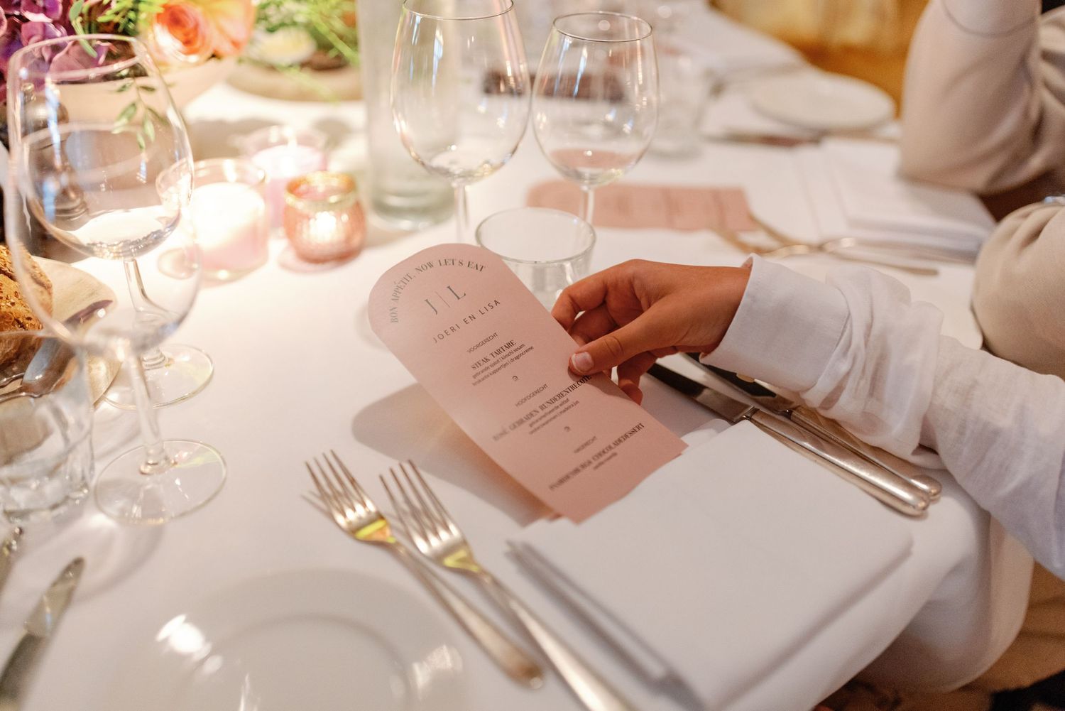 Elegant table settings at a formal dinner with white linens, wine glasses, and menu cards.