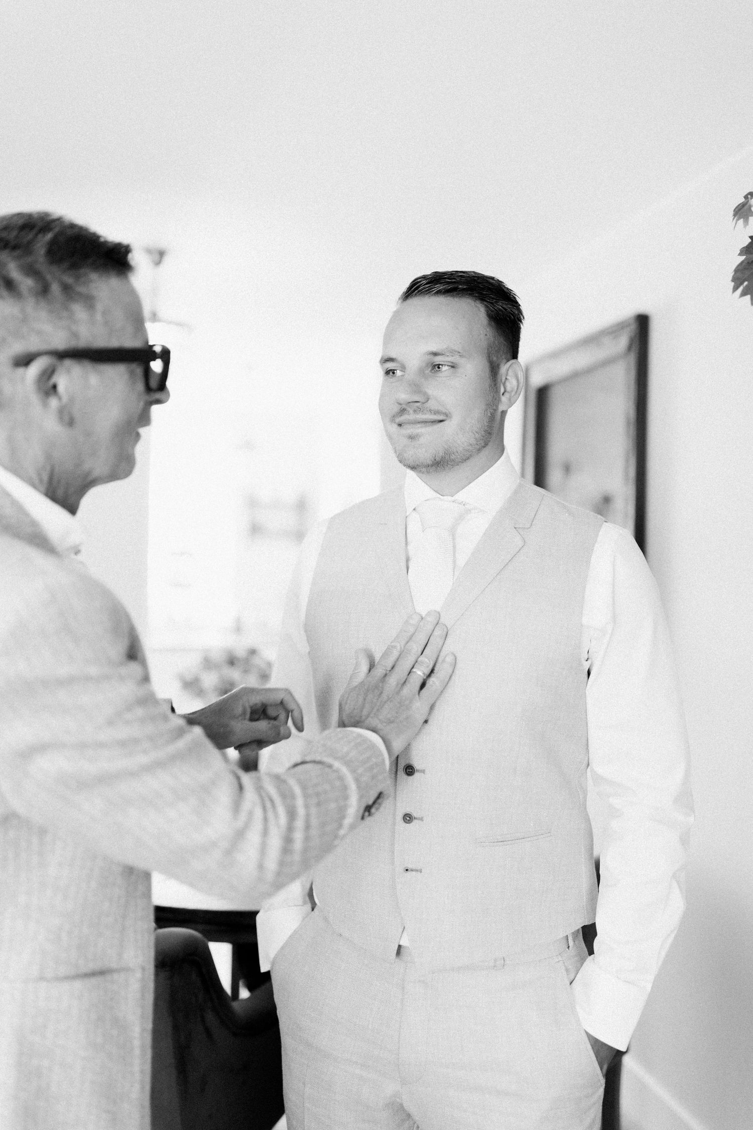 Two people in formal attire having a conversation in a bright interior setting, captured in black and white.