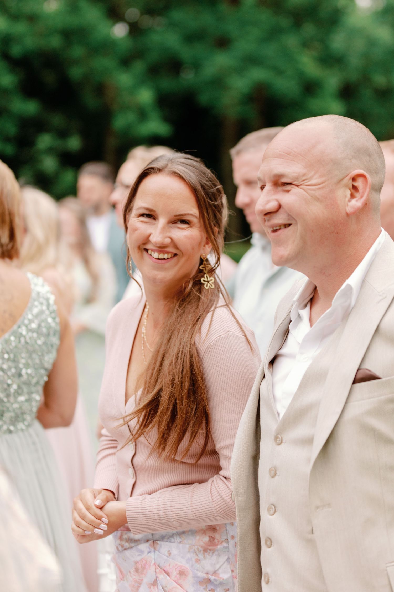 A couple in wedding attire share joyful laughter together during an outdoor celebration.