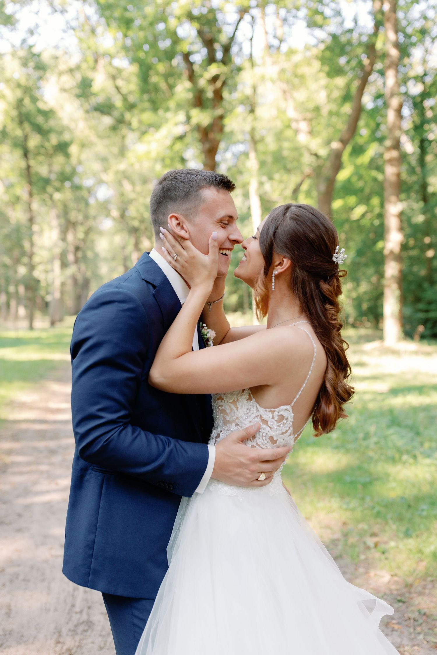 A romantic wedding moment captured on a tree-lined path with soft natural lighting.