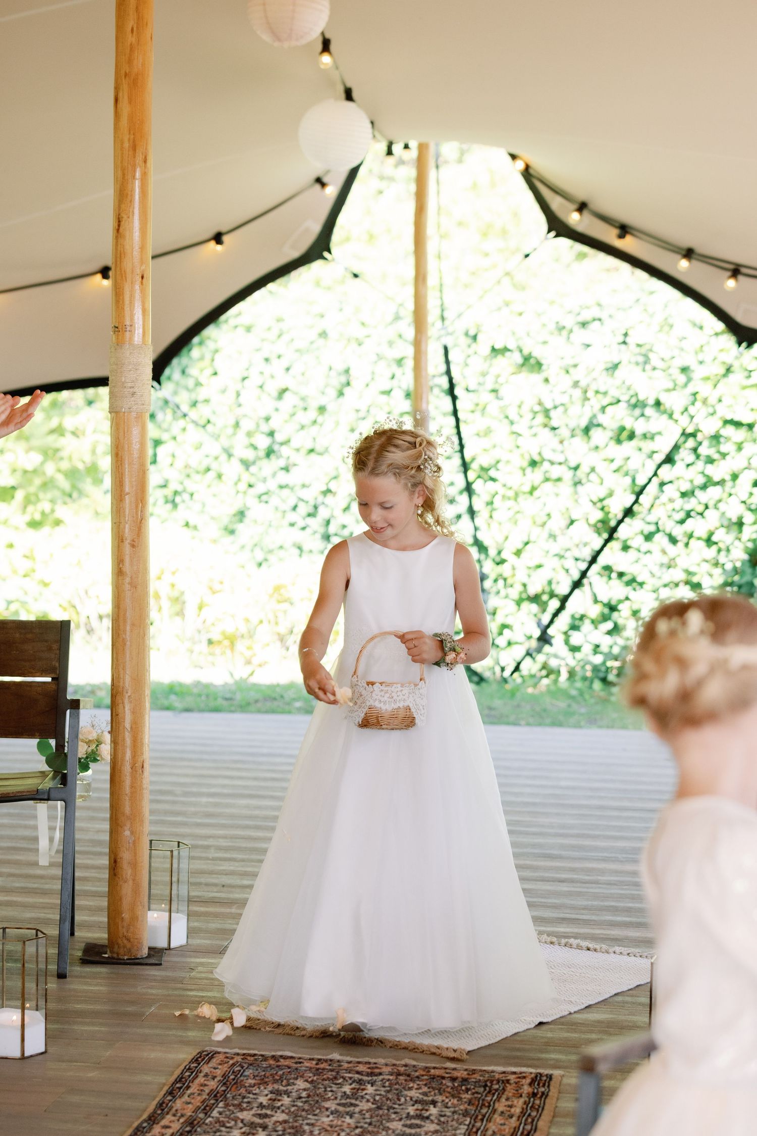 A sequence of photos showing a flower girl in a white dress twirling and dancing under a tented outdoor venue.