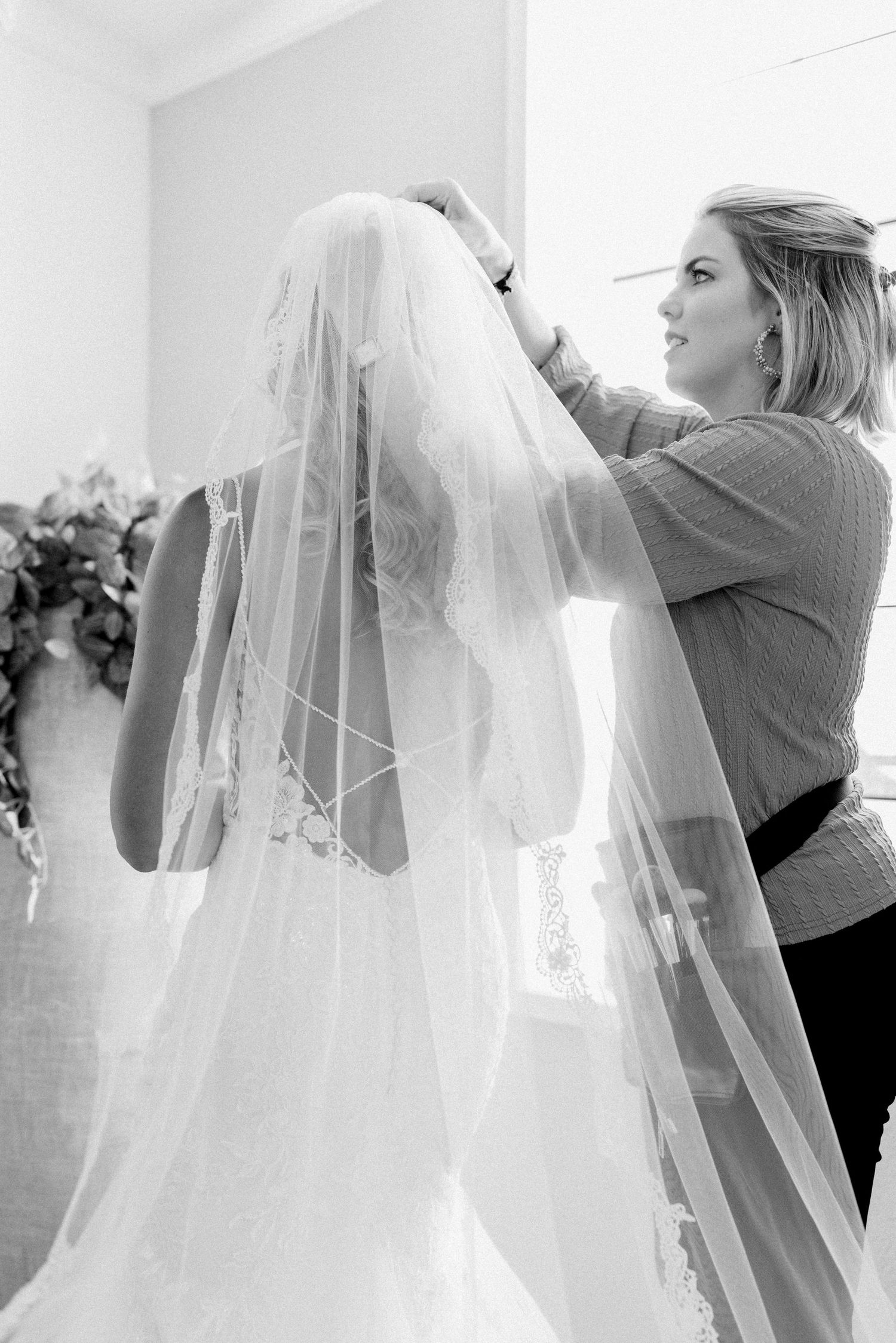 A sequence of black and white photos showing someone adjusting a wedding veil in preparation for a ceremony.