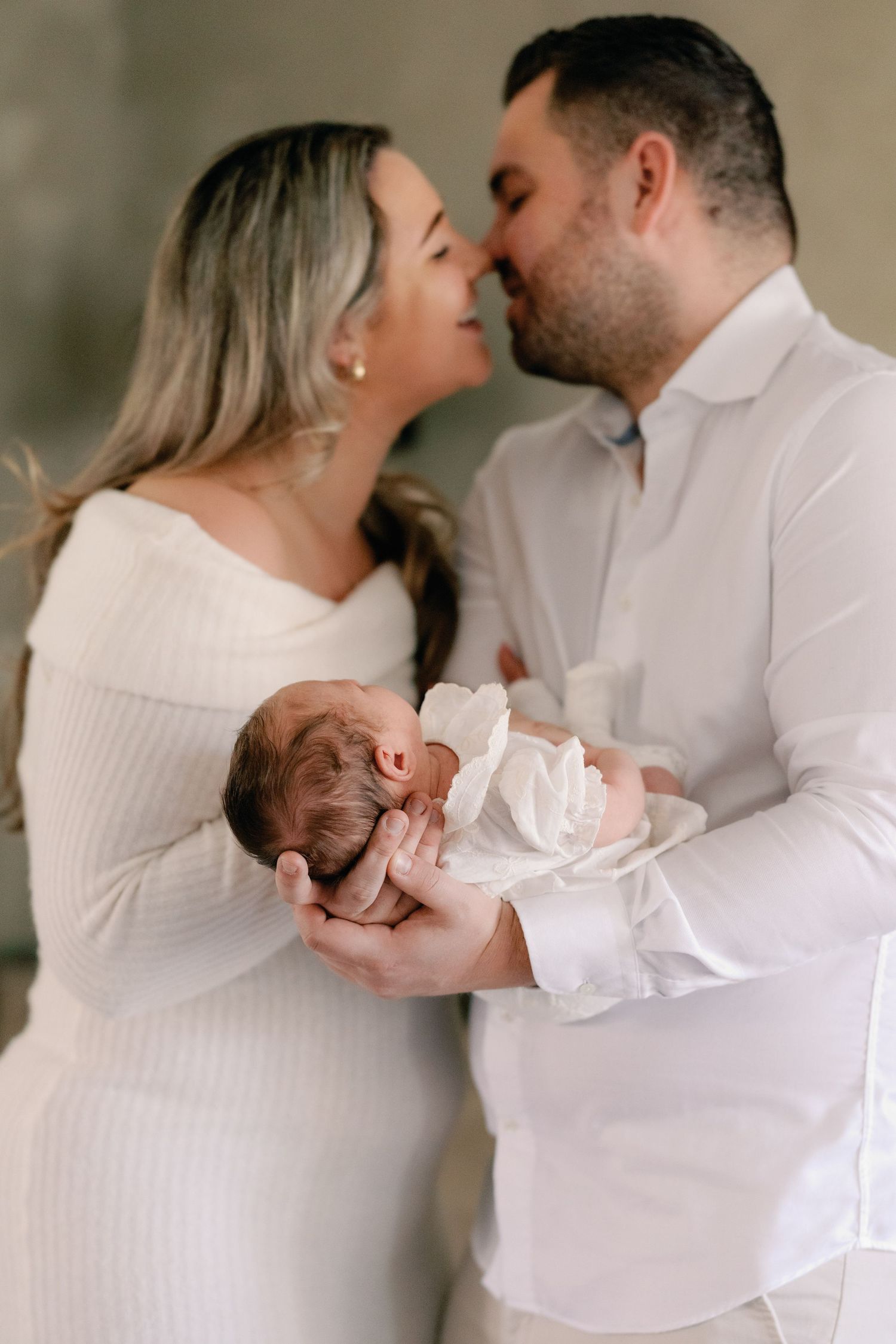 Intimate family portrait series with newborn baby in white clothing.