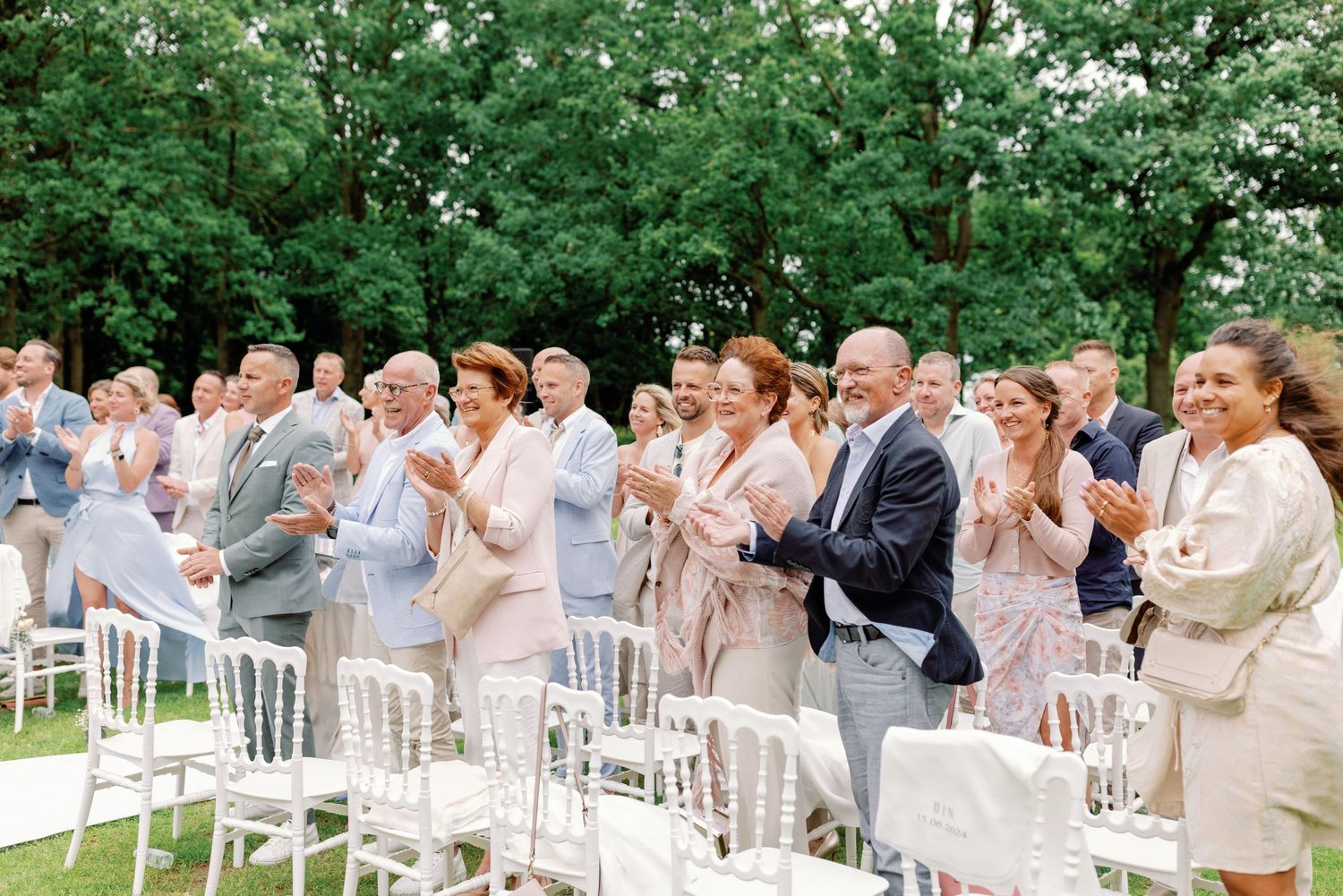 Wedding party members react with surprise and joy during an emotional outdoor ceremony reveal moment.