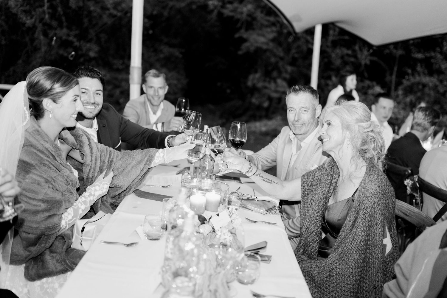 Black and white photo of wedding guests seated at tables during a reception celebration.