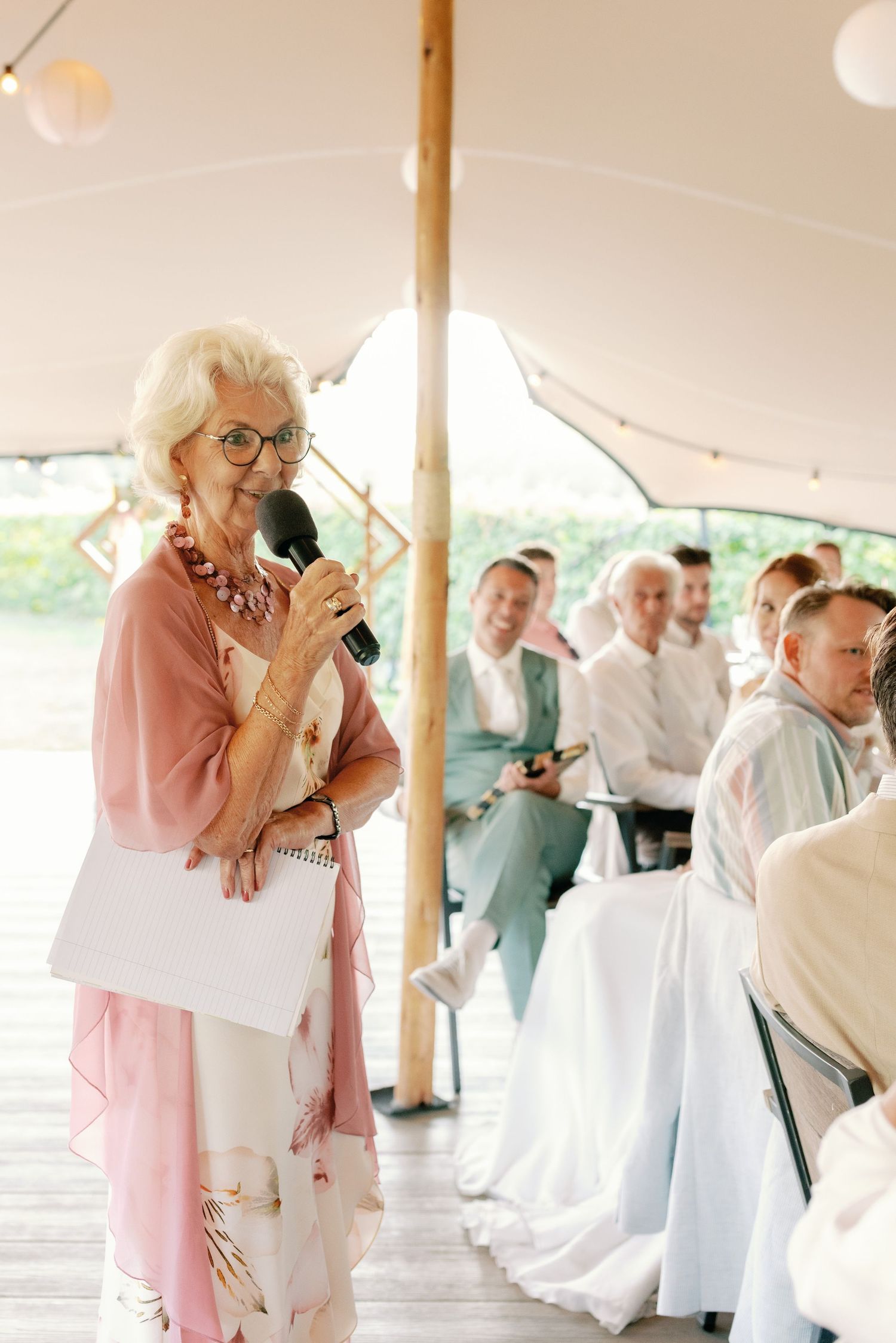 A sequence of photos showing a couple dancing together under a white tent with the person in pink leading.