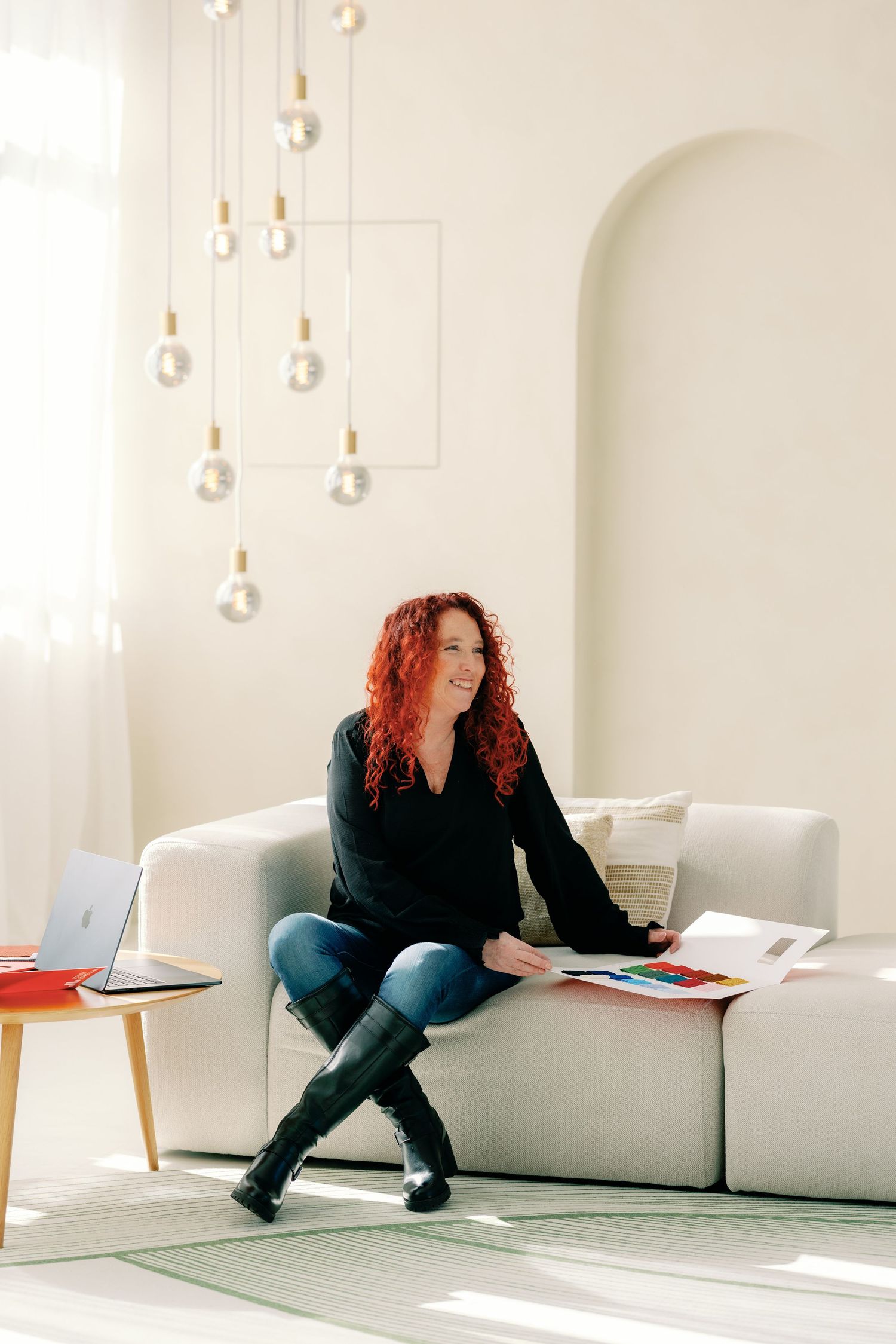 A series of photos showing someone in black clothing sitting against a white wall with hanging pendant lights.