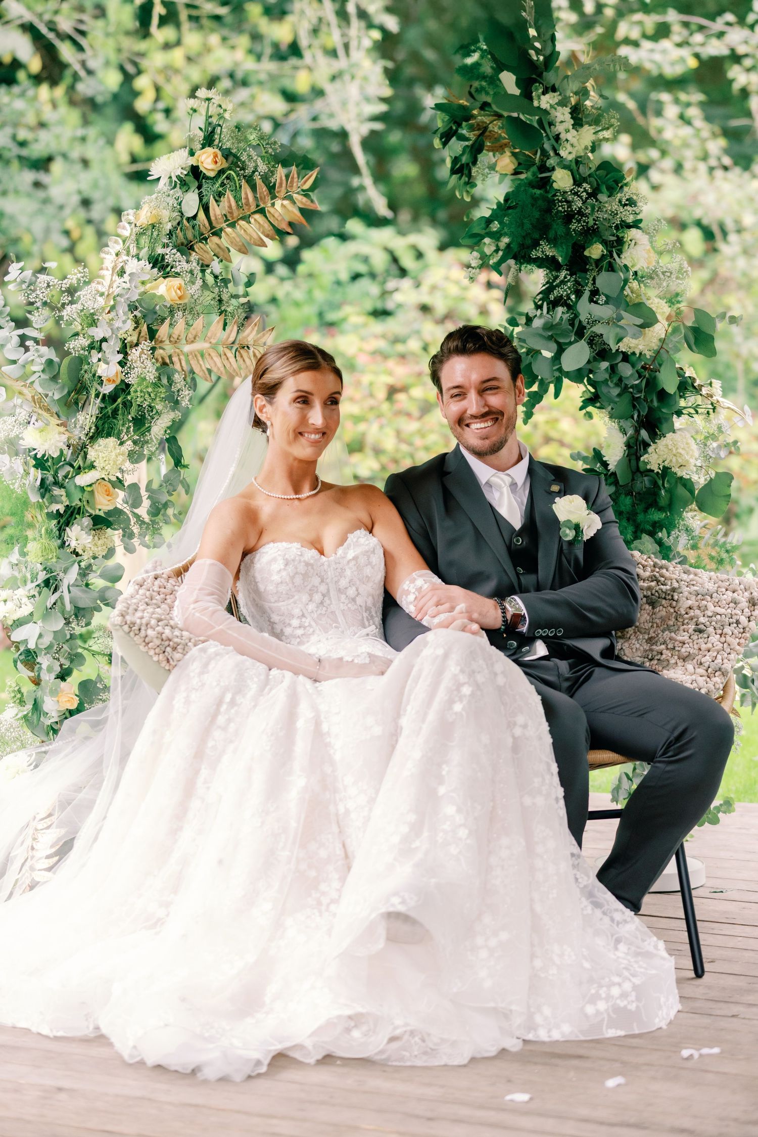 Elegant outdoor wedding scene with lush greenery and decorative backdrop.